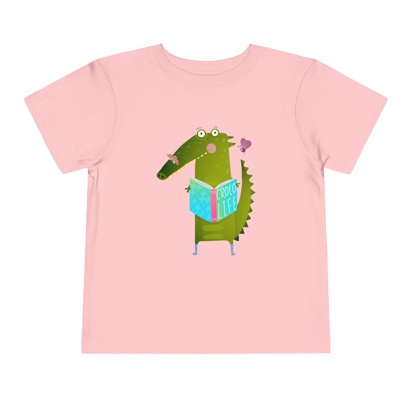 Pink t-shirt with a cartoon crocodile reading a Croc Life book amongst sweet insects