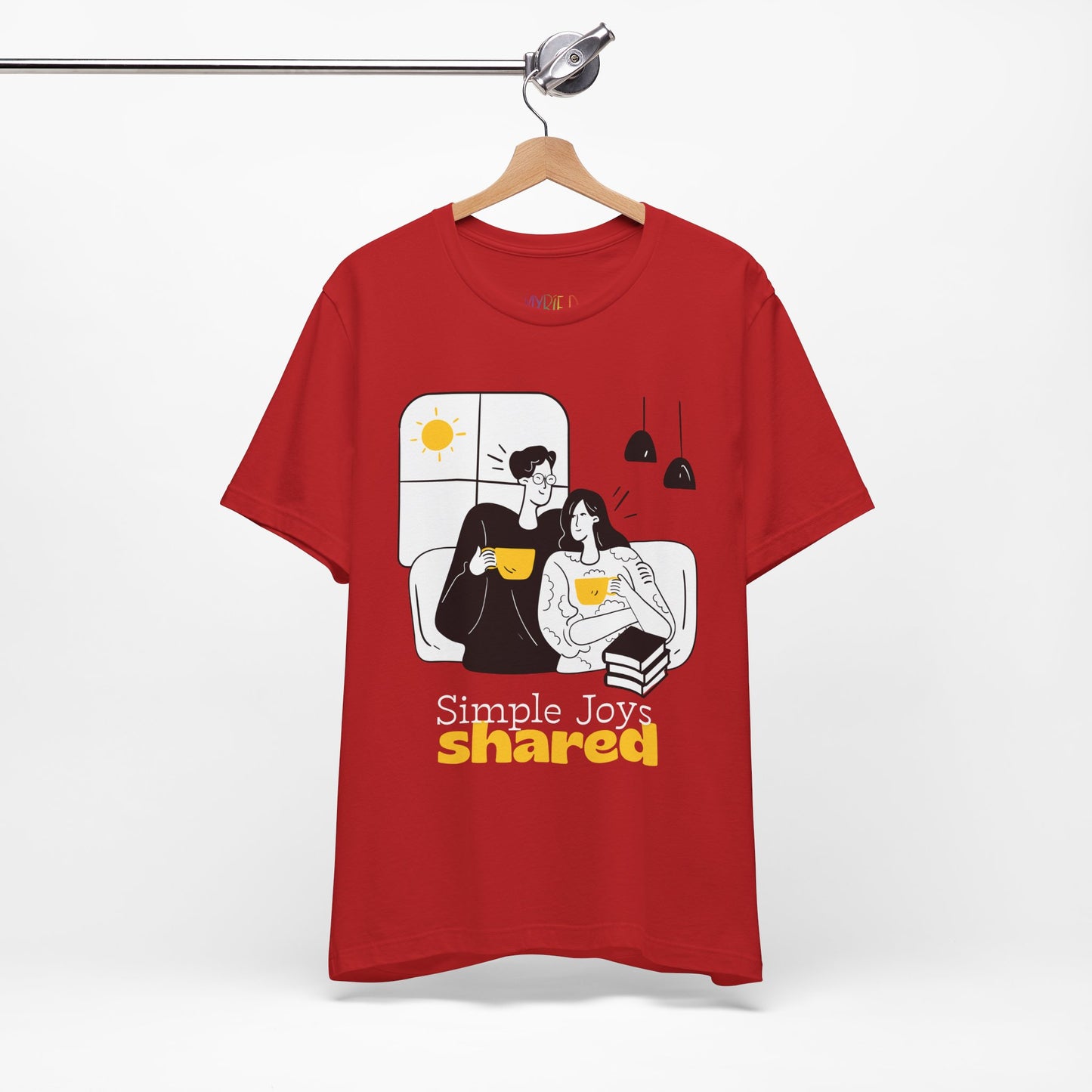 Red t-shirt with a black, white and yellow graphic of a man an d woman snuggled together, drinking coffee, with a stack of books and the words 'Simple Joys Shared' text