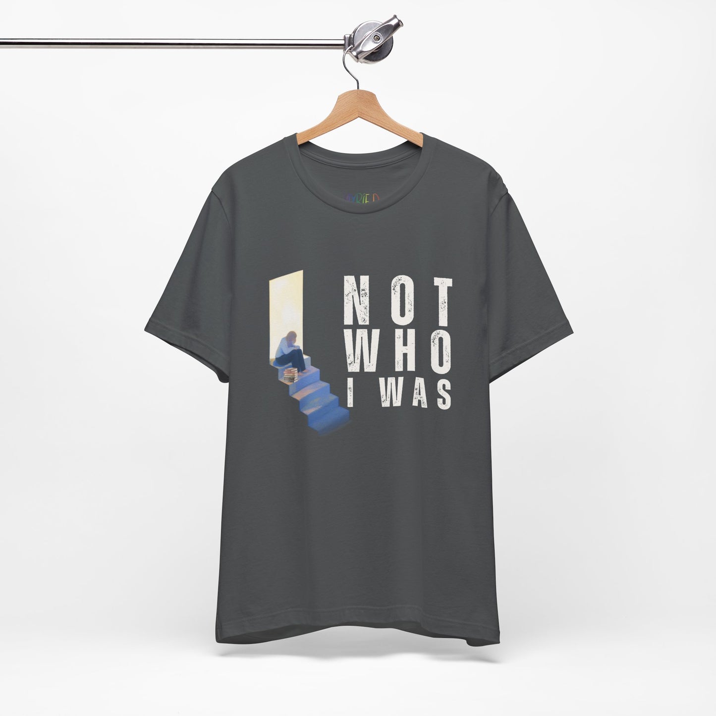Gray t-shirt with person sitting at the top of the stairs, lit from behind and text 'Not Who I Was'