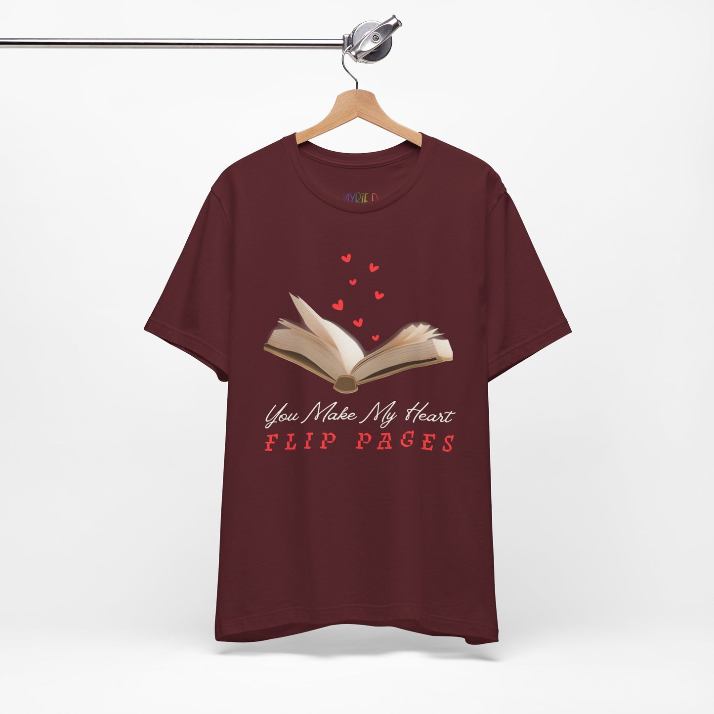 Maroon t-shirt with a graphic of an open book with hearts floating from the pages and text 'You Make My Heart FLIP PAGES'