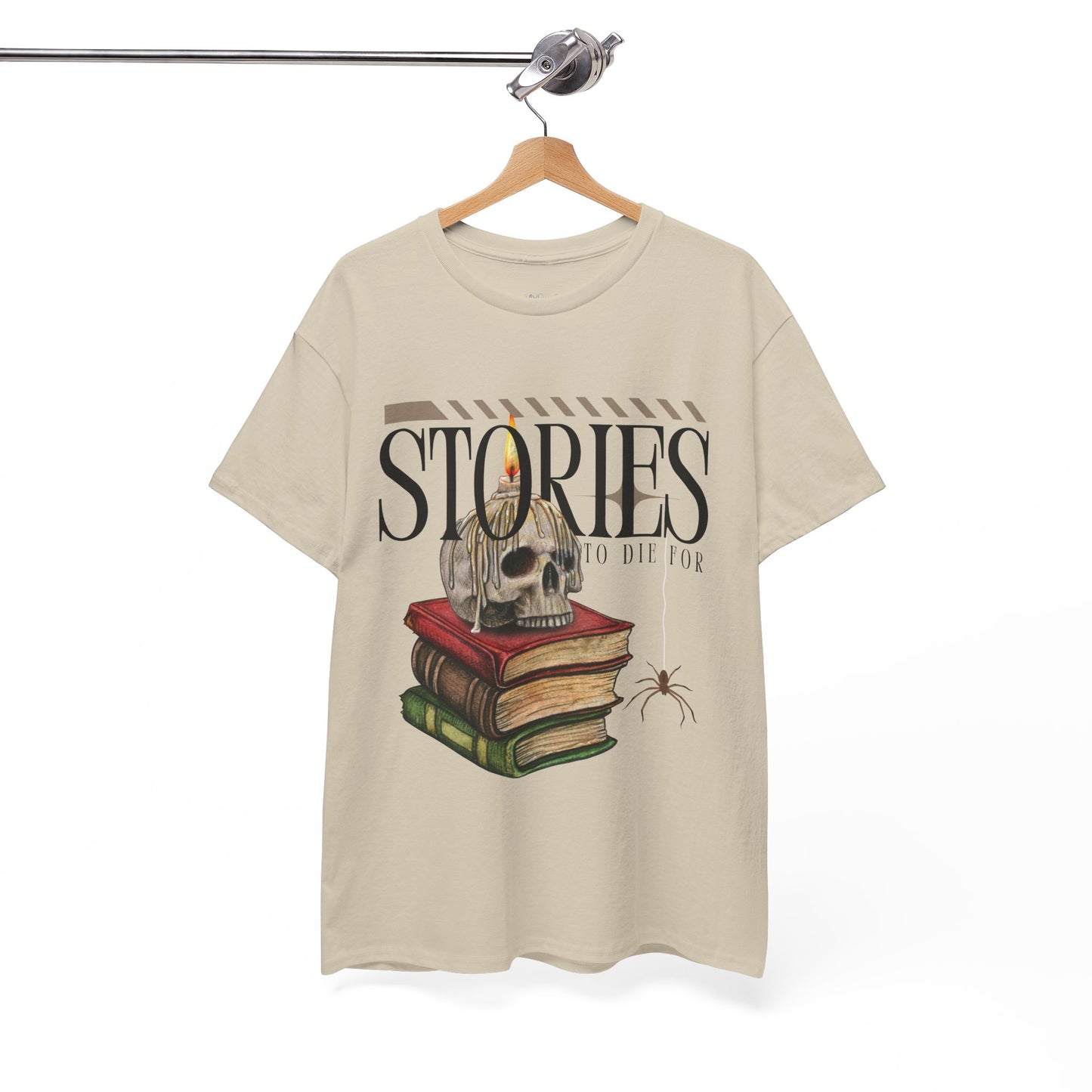 Tan t-shirt with skull on top of a stack of books, a candle dripping wax on it's head, a spider dangling and text 'Stories To Die For'