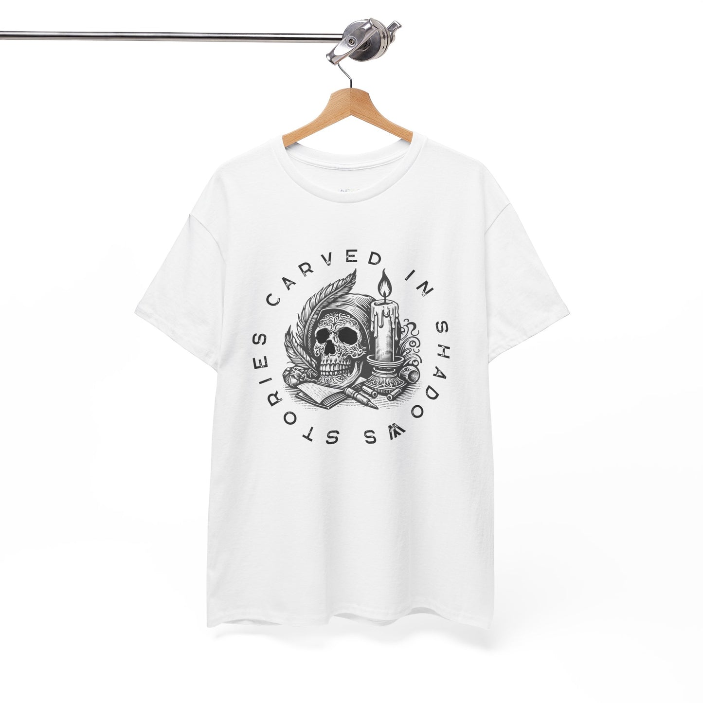 White t-shirt with white graphic design of a creepy skull, books, candle and feathers with text 'Stories Carved In Shadows' on a hanger against a white background