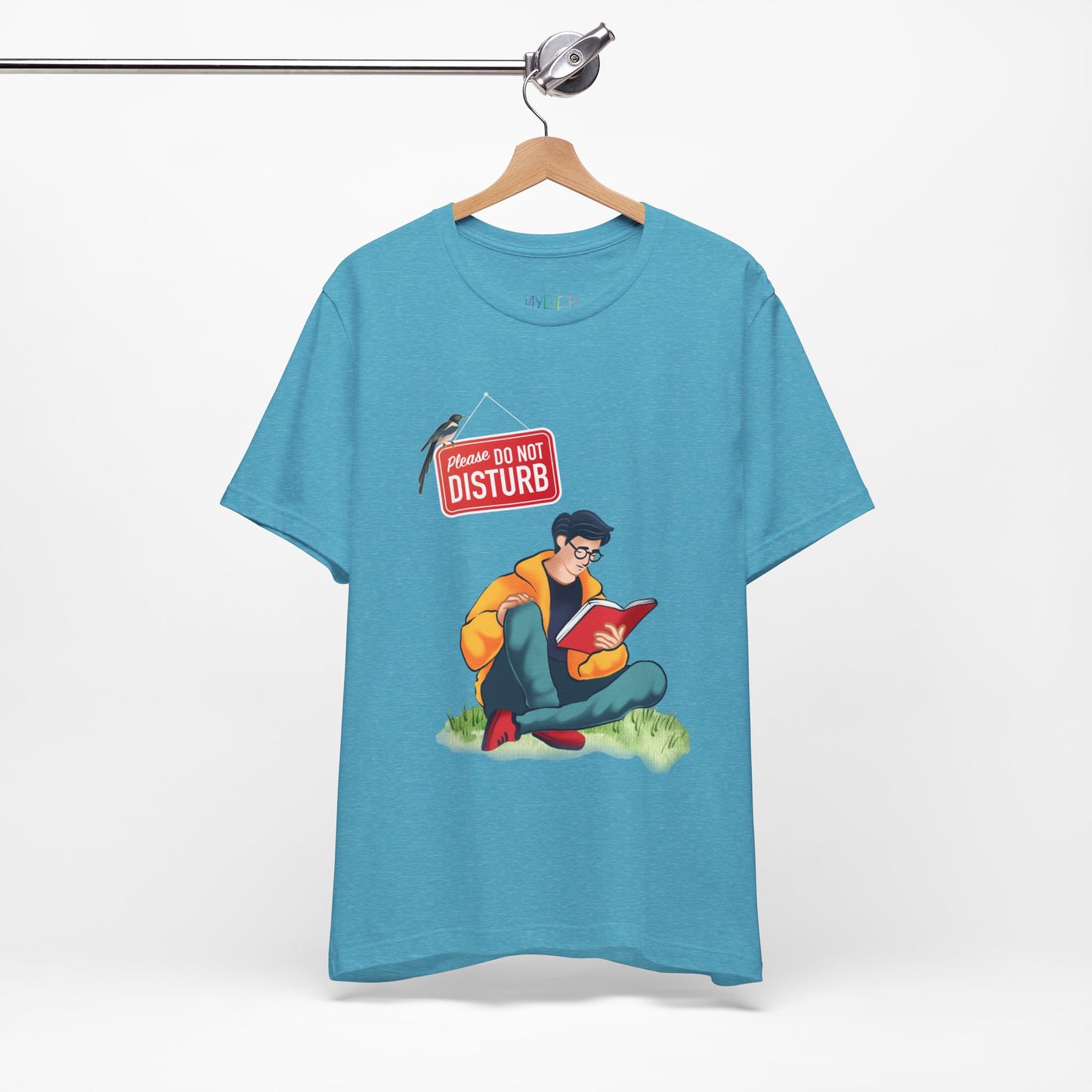 Light aqua blue t-shirt with a graphic of a person sitting in the grass reading a book, and a bird perched atop a 'Do Not Disturb' sign