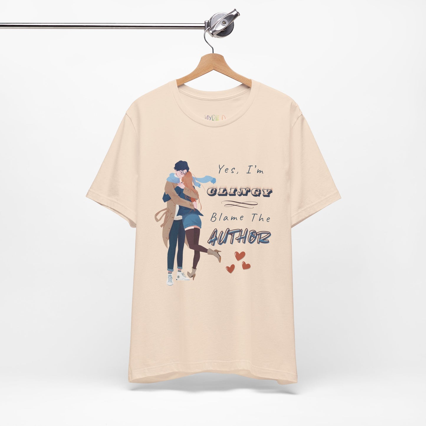 Beige t-shirt with graphic design of a woman snuggled up to a man and text " and text on a white background 'Yes, I'm CLINGY. Blame The Author.'