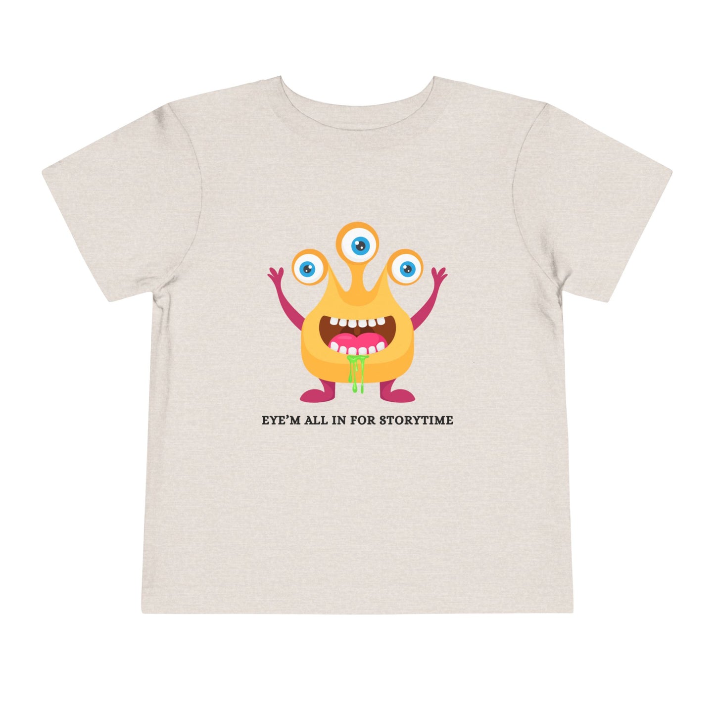 Beige toddler t-shirt with a drooling, three-eyed monster graphic and text 'Eye'm all in for storytime' on a white background