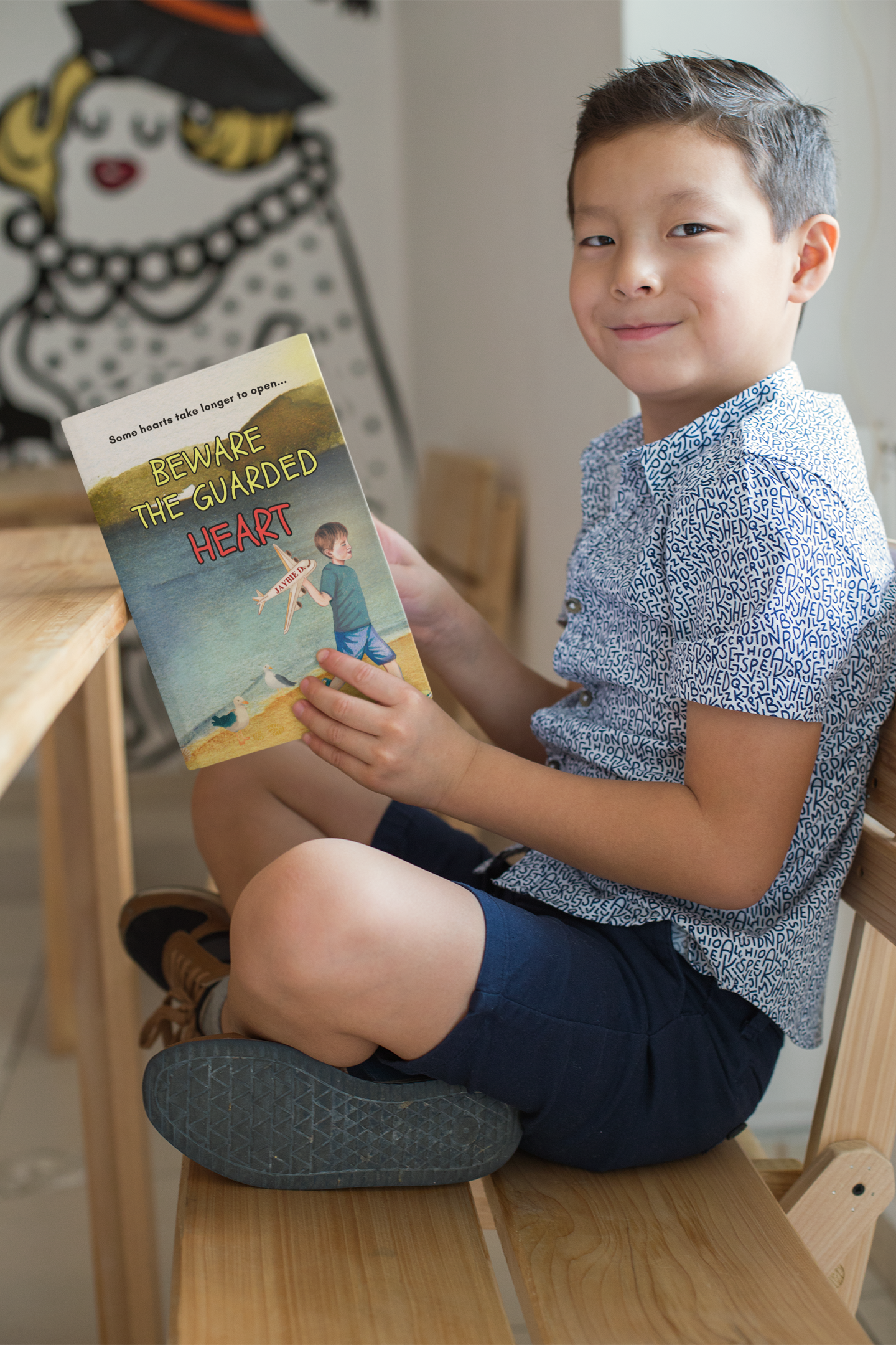Young reader smiling while holding a copy of Beware The Guarded Heart by Jaybie D, a thoughtful picture book about emotional growth, trust, and opening your heart to connection and belonging