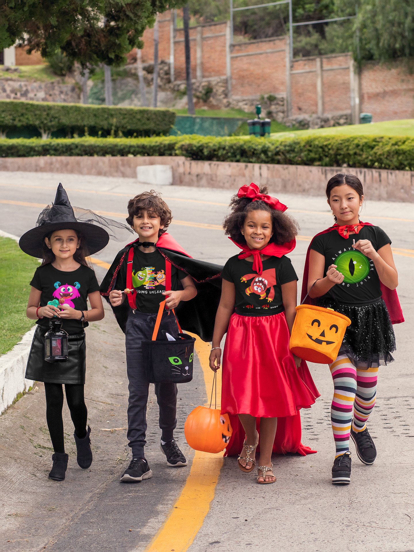 Four children in Halloween costumes, wearing t-shirts by Jaybie D. and walking down the road with trick-or-treat pails.