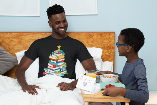 Dad wearing a Christmas t-shirt in bed as son brings him breakfast.