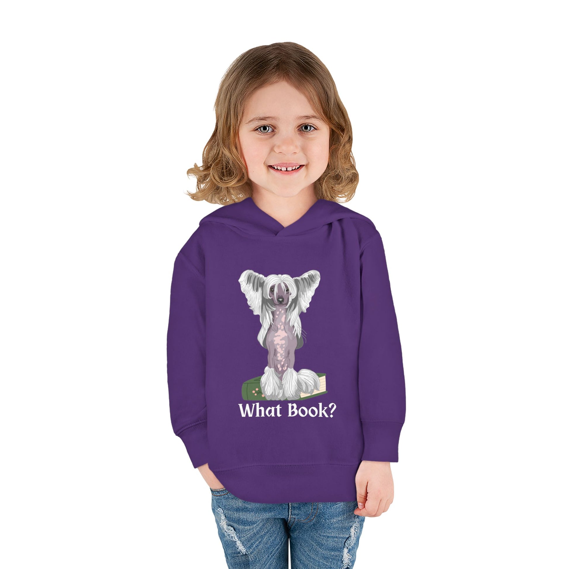 Girl wearing a purple toddler hoodie featuring a partially hairless dog perched on top of a book and text 'What Book' on white background
