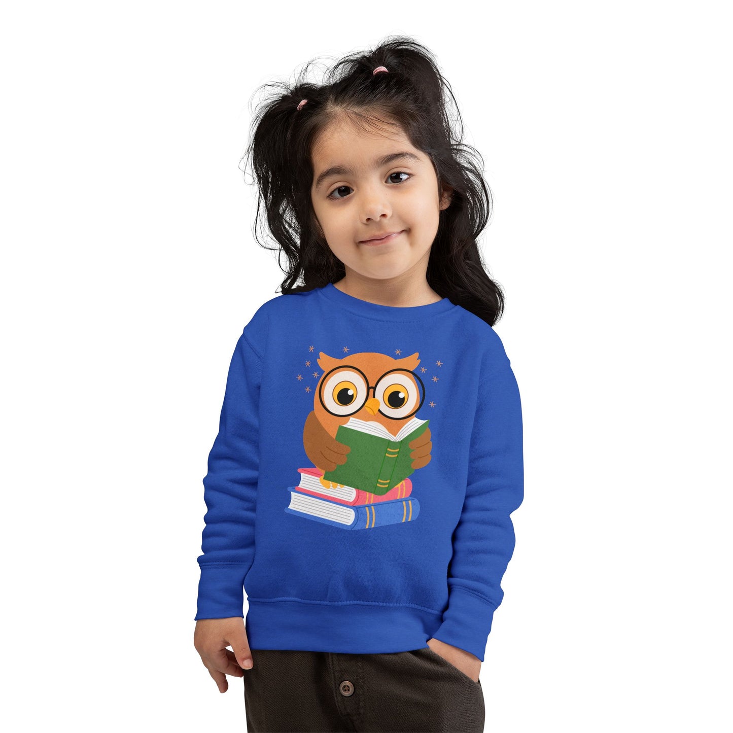 Girl wearing a blue toddler sweatshirt with an owl reading a book 