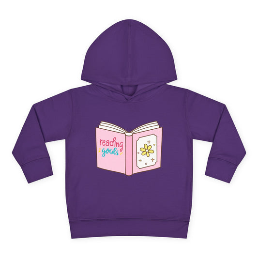 Pink cartoon book with sparkly stars and the words “Reading Goals” in playful lettering — printed on a soft toddler hoodie.