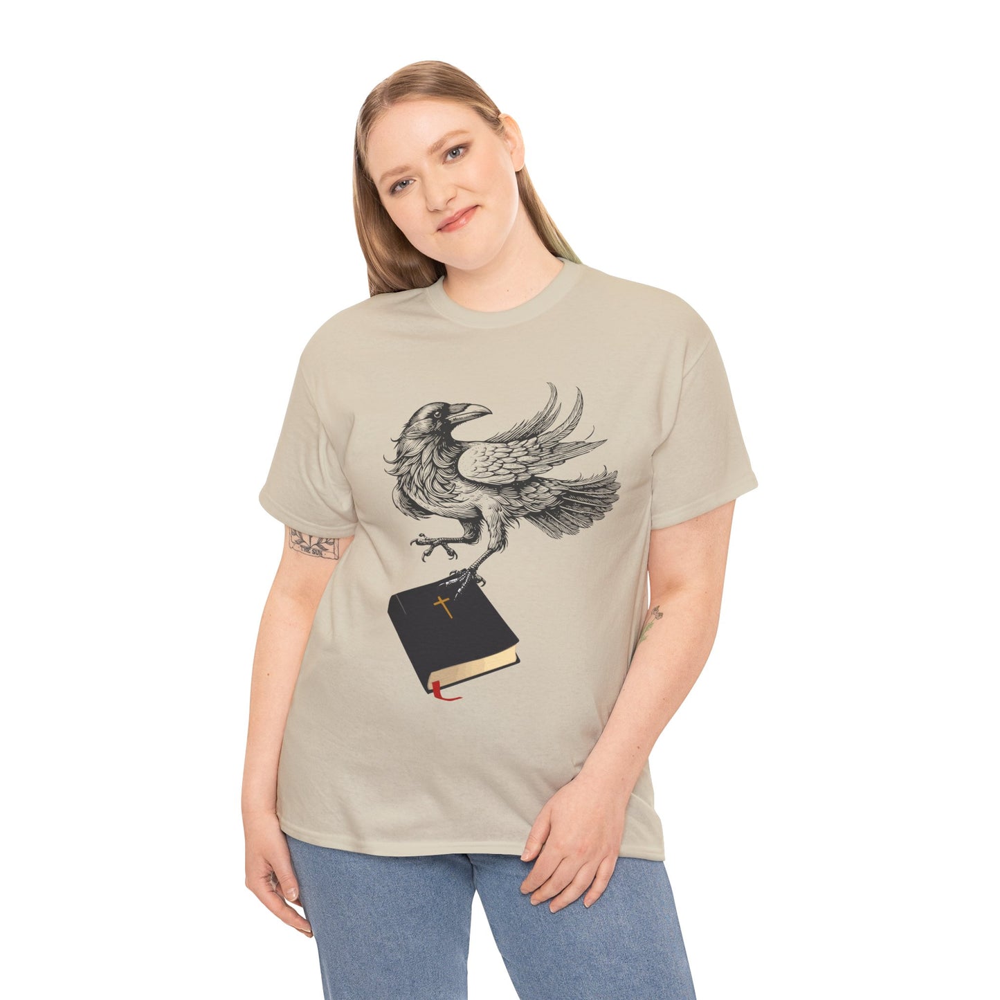 Woman wearing a tan t-shirt with a crow carying a bible, a shirt on a hanger against a white background