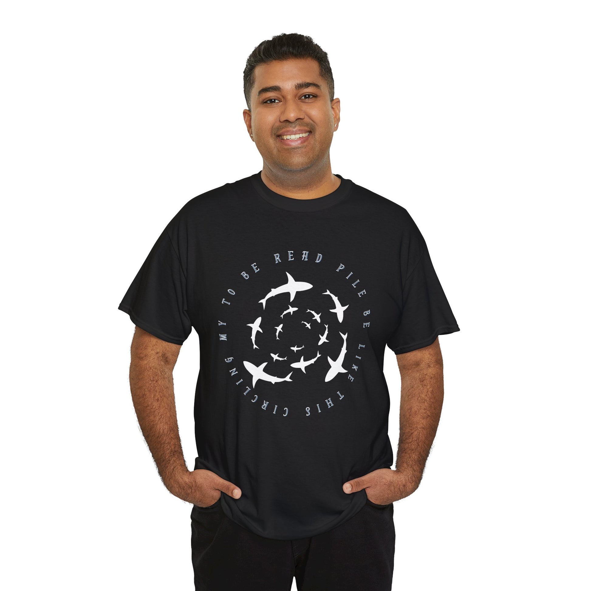 Man wearing a black t-shirt with white graphic sharks in various sizes circling and text 'circling my to be read pile be like this' 
