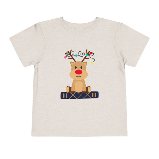 Beige t-shirt with a baby reindeer sitting on a book. 