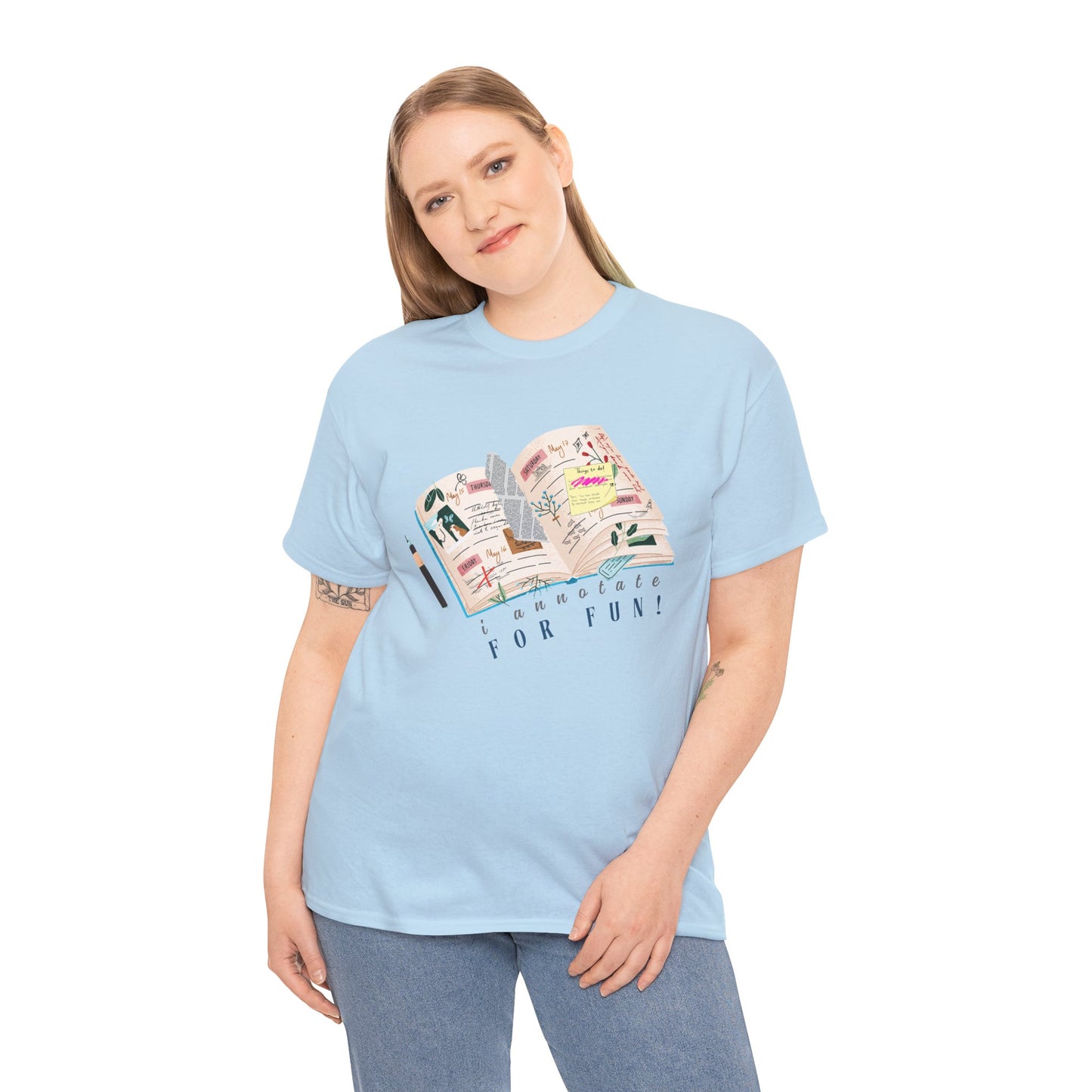 Woman wearing a ight blue t-shirt with a An open scrapbook full of scribbles, tickets, newspaper clippings and more, text 'I Annotate For Fun' 