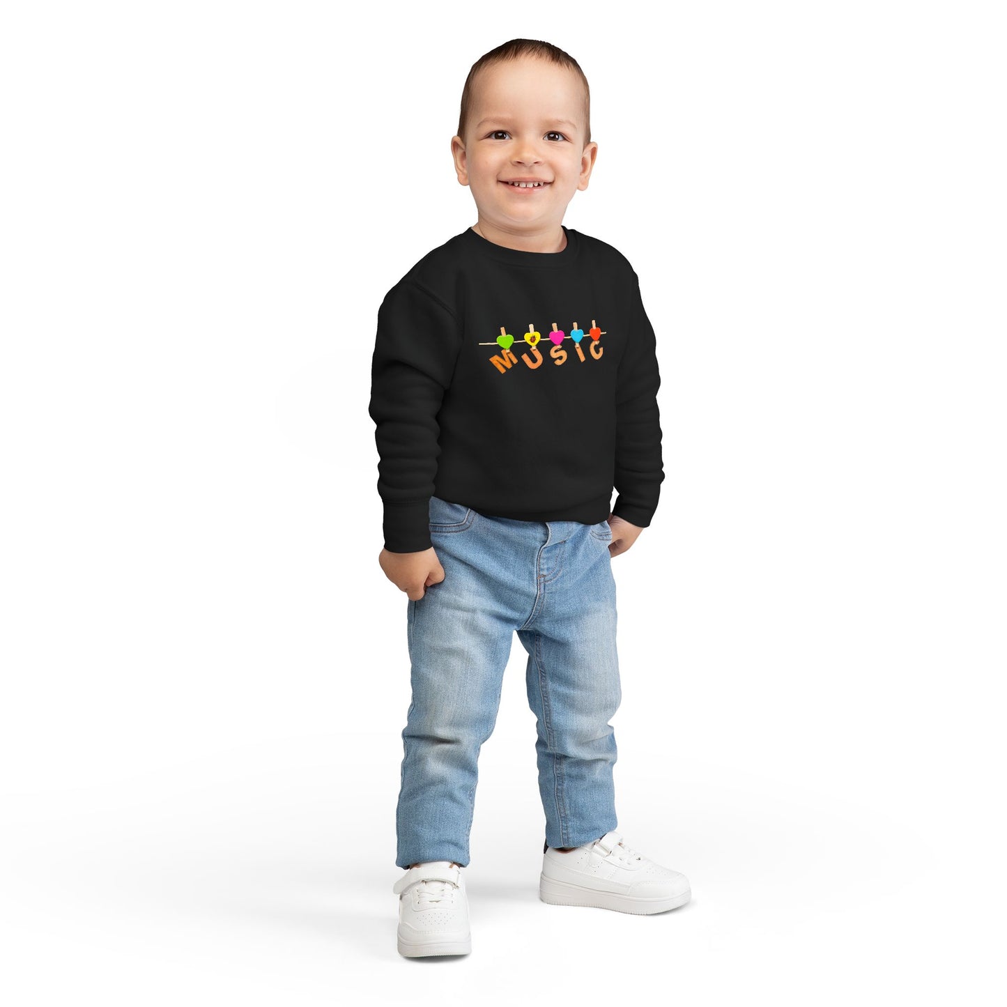 Boy wearing a black toddler sweatshirt with colorful letters hanging with clothespins to spell 'MUSIC'