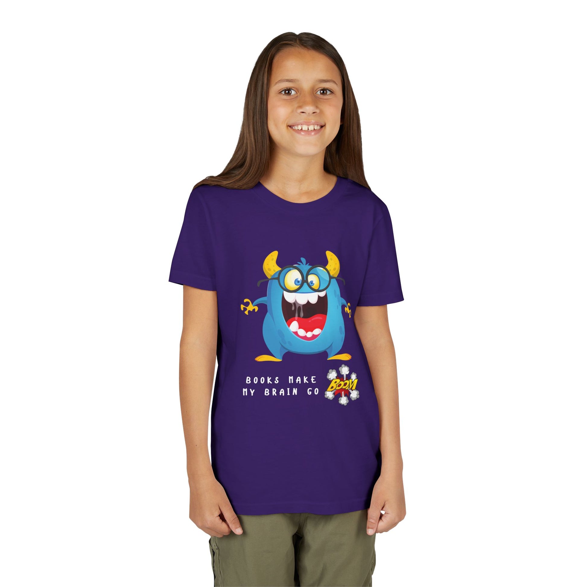 Girl wearing a purple t-shirt with a a very excited blue and yellow cartoon monster, mouth wide open and text 'Books Make My Brain Go BOOM'