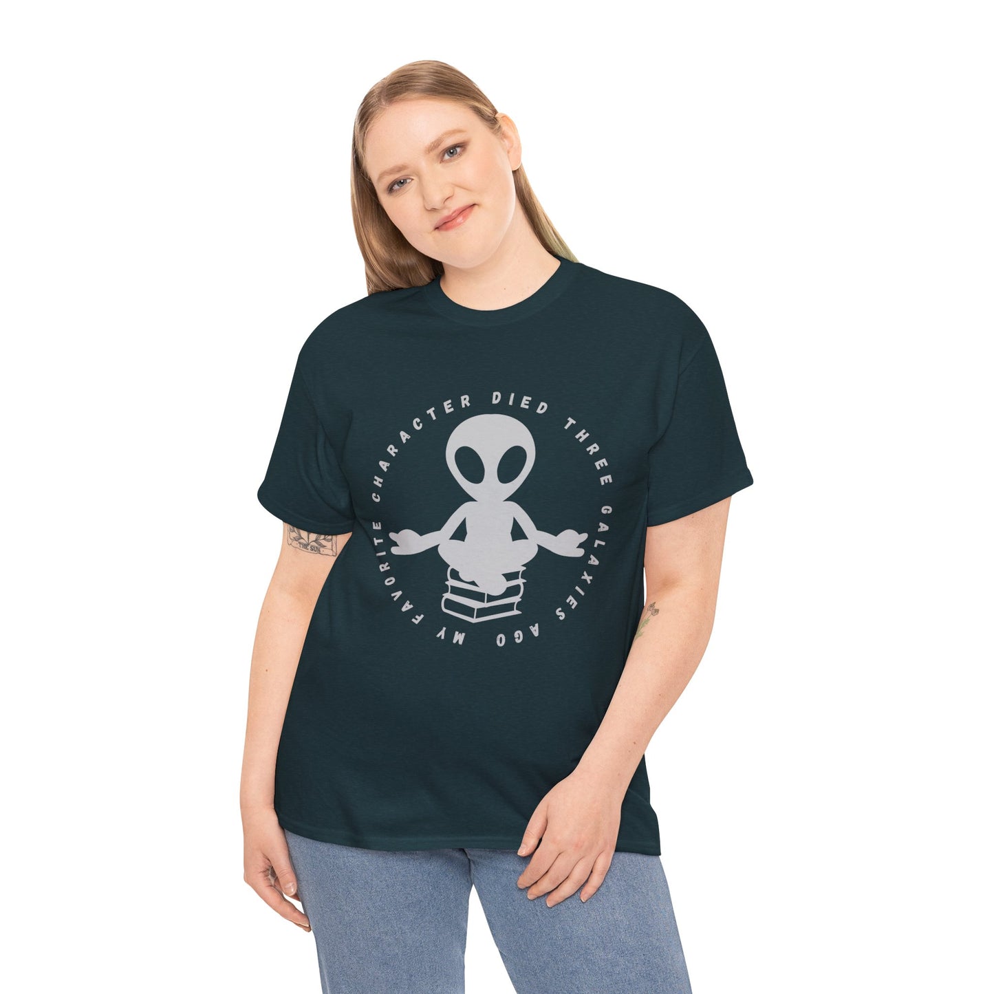 Woman wearing a dark t-shirt with meditating alien sitting on a stack of books, circled by text 'My Favorite Character Died Three Galaxies Ago' 