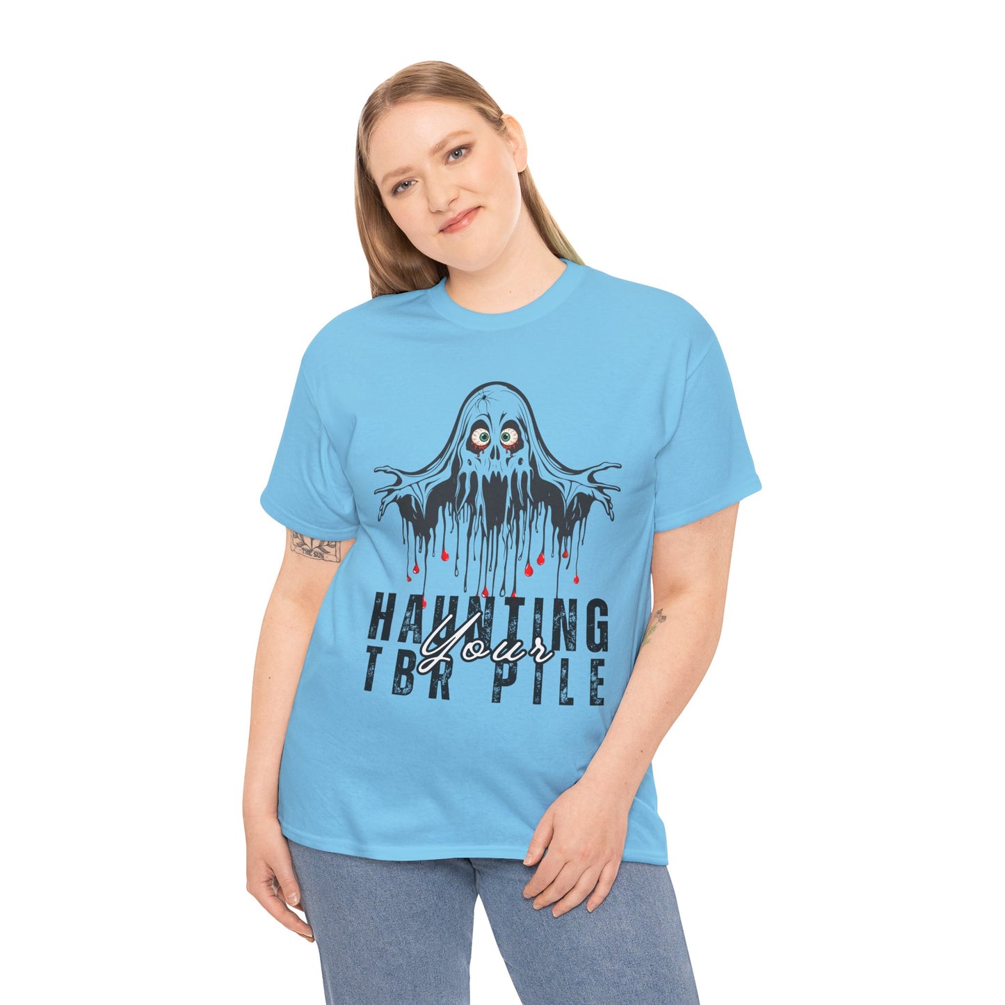 Woman wearing a light blue t-shirt with ghost graphic and text 'Haunting Your TBR Pile' on a hanger against a white background