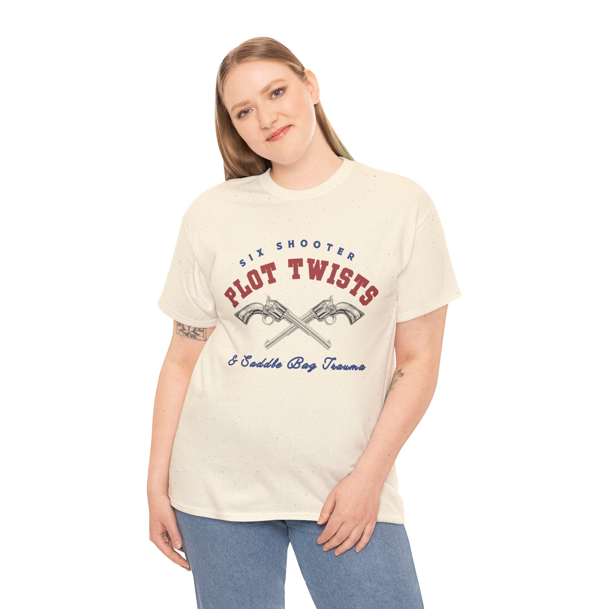 Woman wearing a beige t-shirt with two pistols criss-crossed in the center and text 'Six Shooter Plot Twists & Saddle Bag Trauma'
