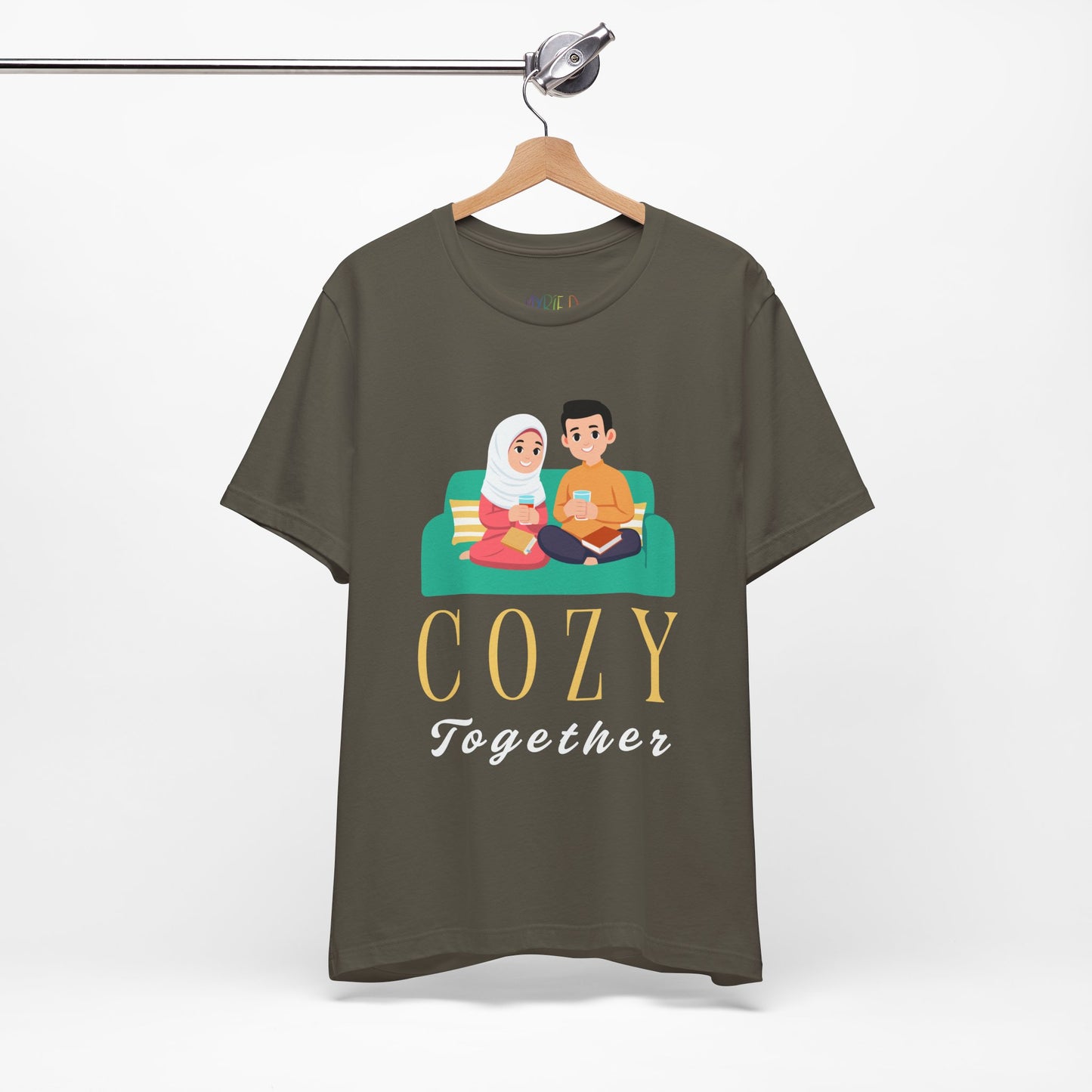 Green t-shirt with a graphic of two people on a couch, with books and drinks, the text 'Cozy Together' sits beneath in large letters
