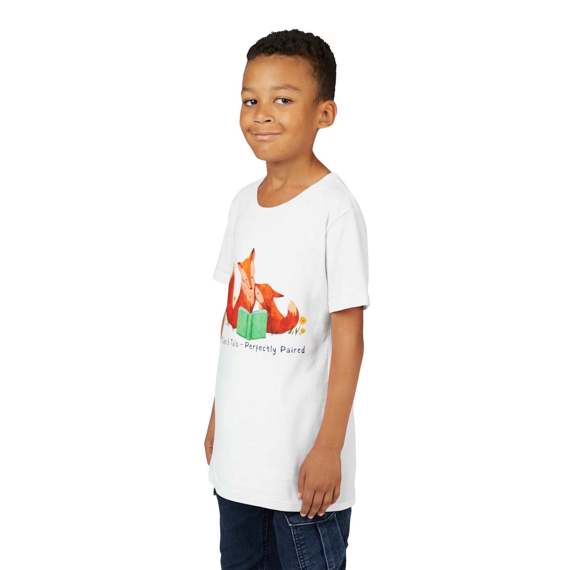 Boy wearing a white t-shirt with fox family reading a book and text 'tales & tails - perfectly paired'