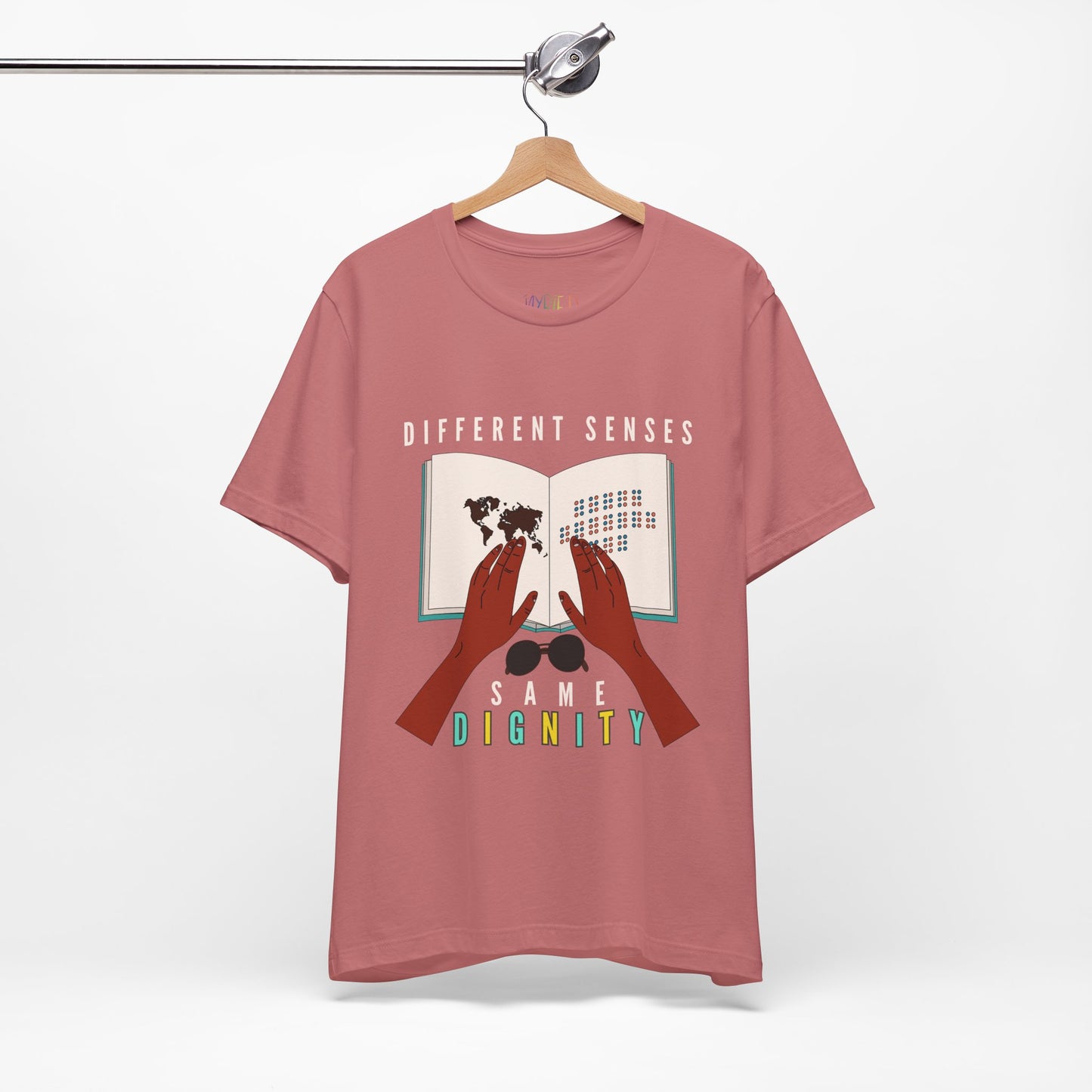 Mauve t-shirt with graphic of two hands touching a braille book and text 'Different Senses, Same Dignity'