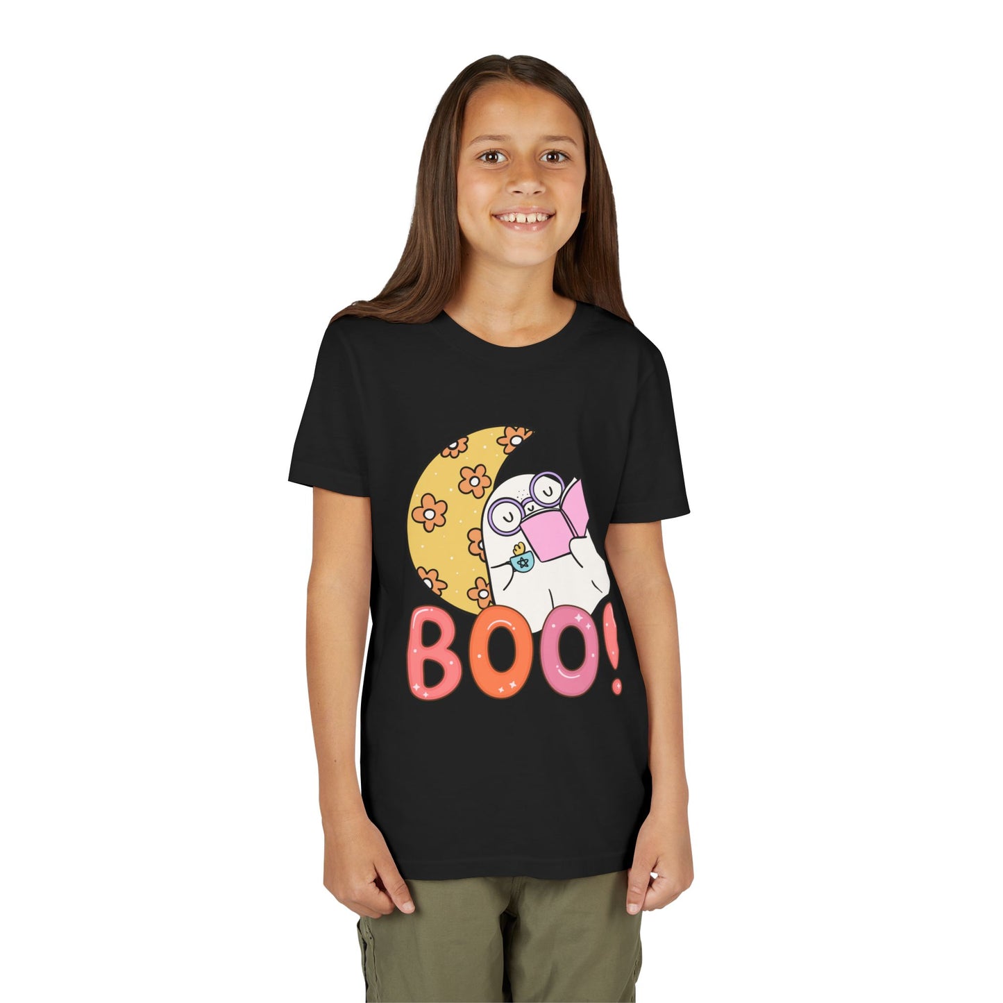 Girl wearing a black t-shirt with a cartoon ghost leaning on a crescent flowered moon with a hot beverage and a good book, text 'BOO!' in large letters 