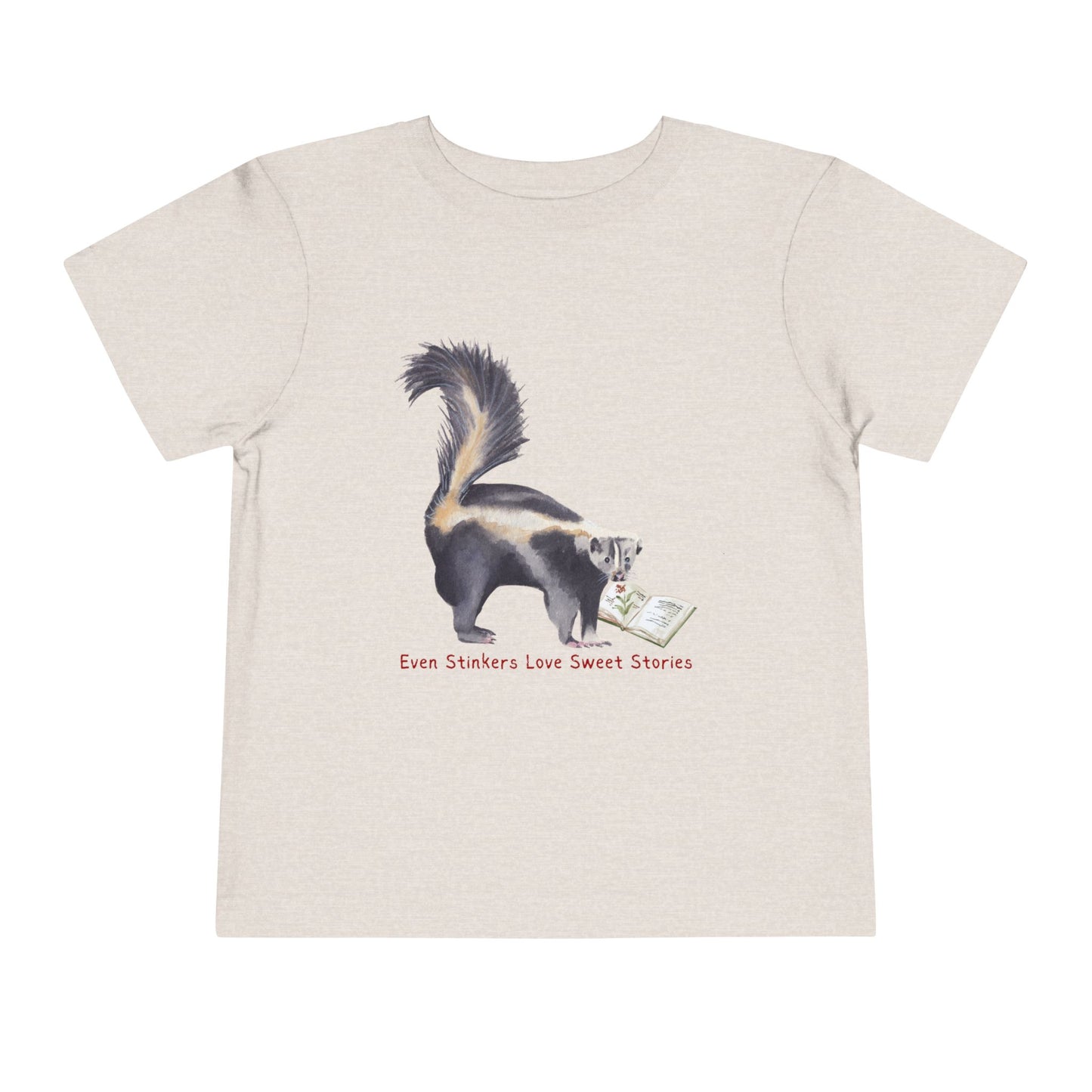 Tan toddler t-shirt with a skunk reading a book and text 'Even Stinkers Love Sweet Stories' 