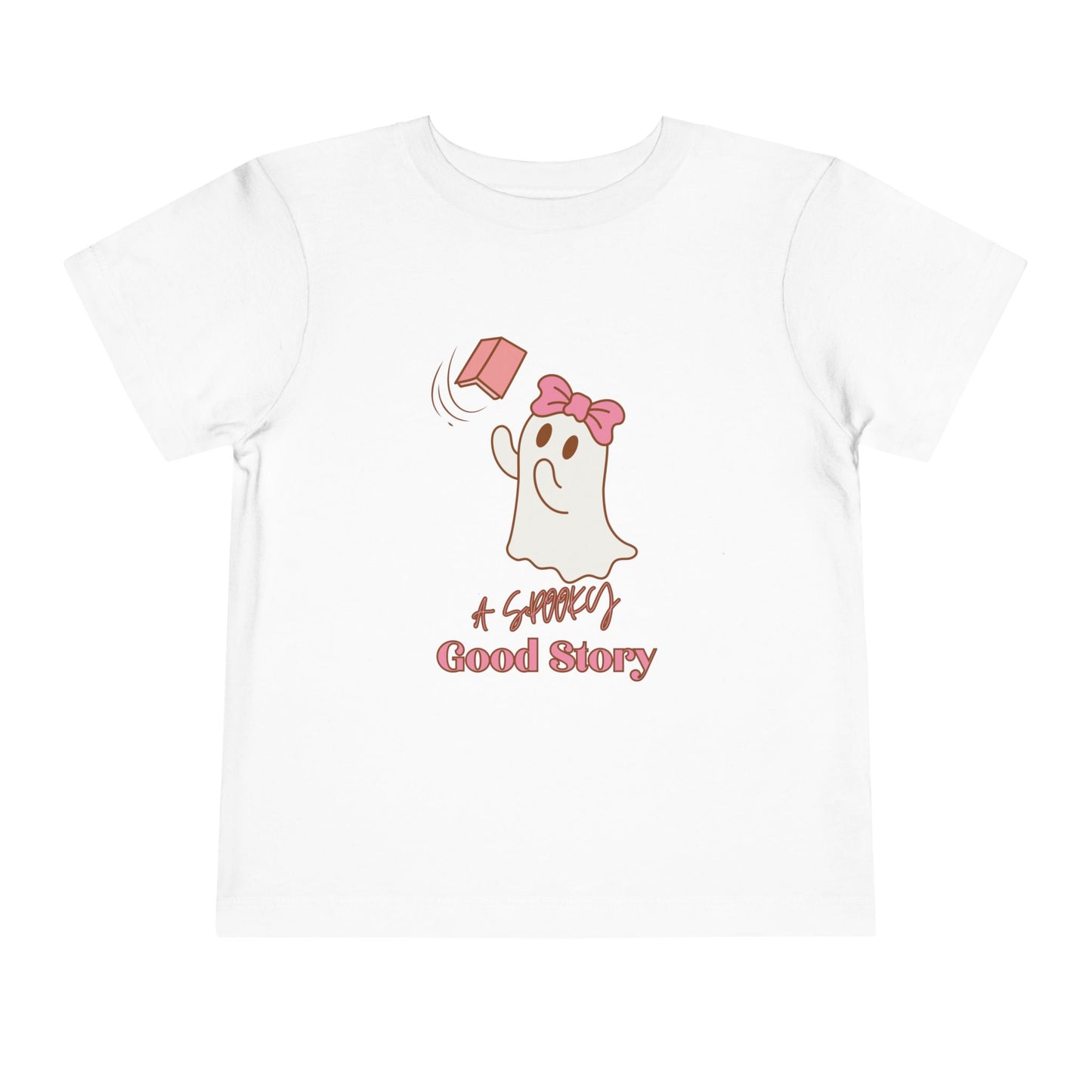 White toddler t-shirt with a ghost trying to catch a floating pink book with text 'A SPOOKY GOOD STORY'