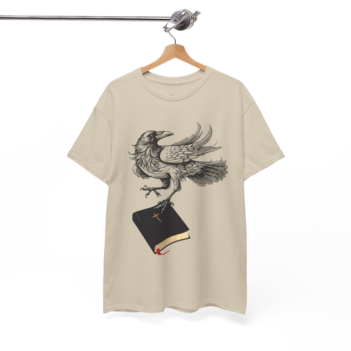 Tan t-shirt with a crow carying a bible, a shirt on a hanger against a white background