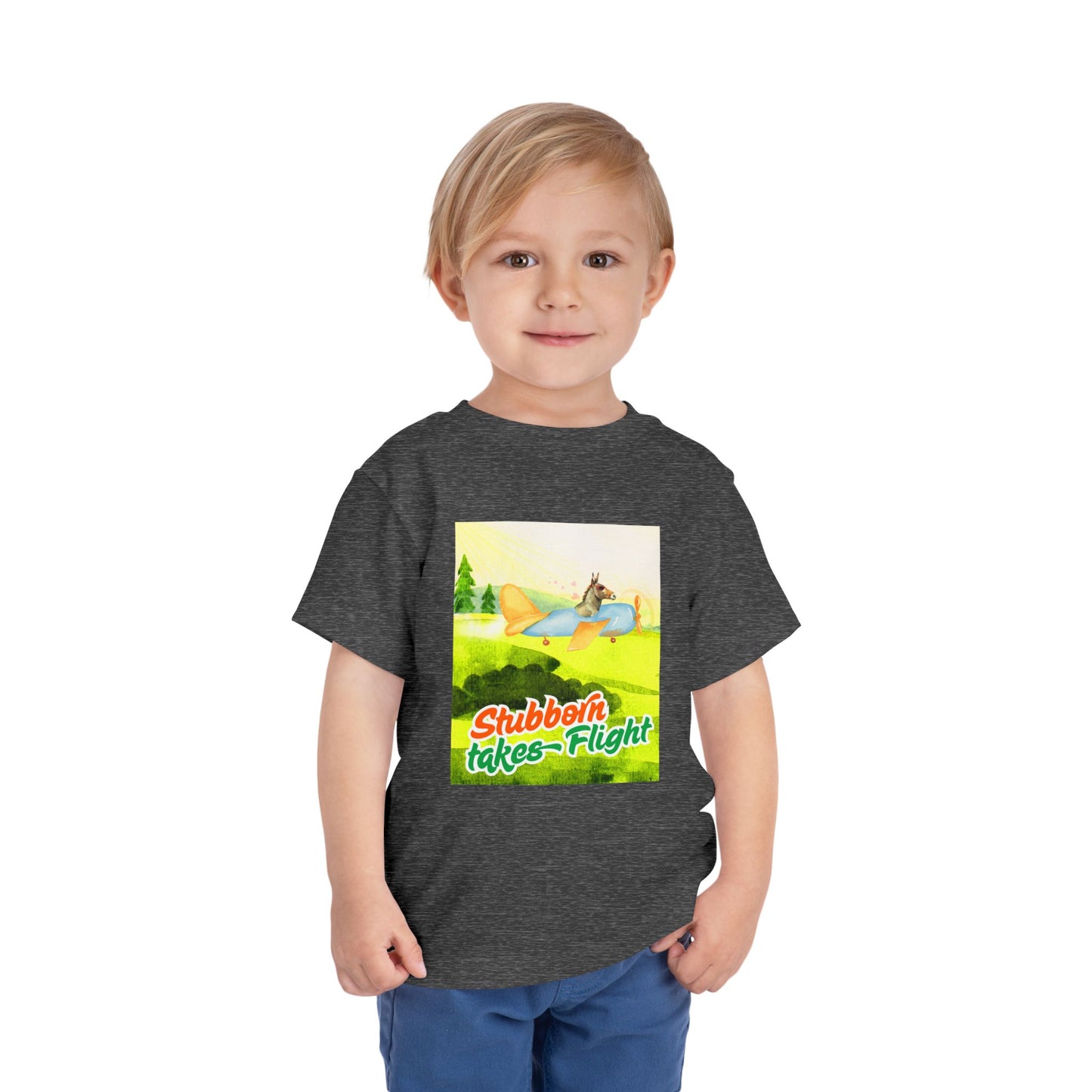 Child wearing a gray toddler t-shirt with a colorful graphic of a a donkey flying an airplane, with text 'Stubborn takes Flight' 