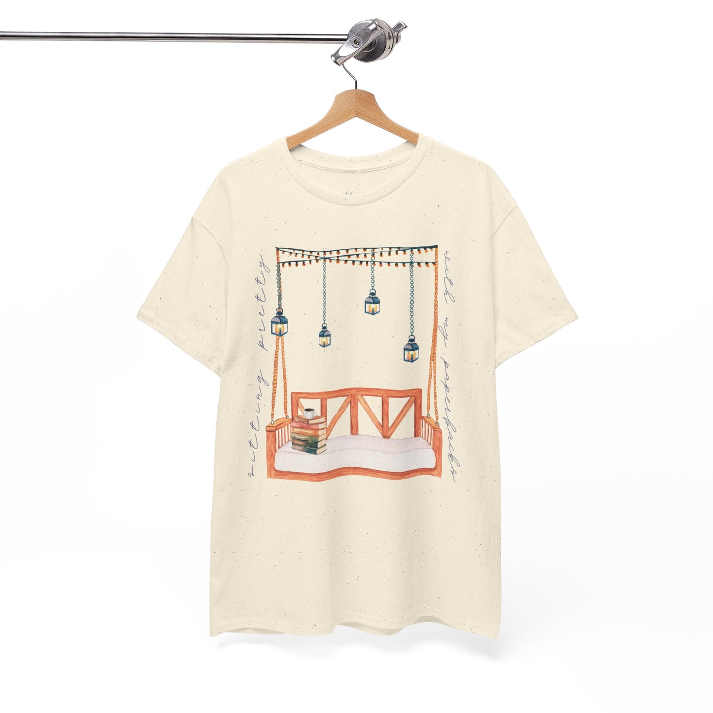Beige t-shirt with a porch swing, string lights, hot beverage and a stack of books, text says 'Sitting Pretty With My Paperbacks'