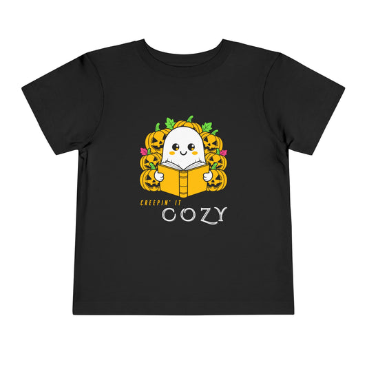Black toddler t-shirt with a ghost reading a book in pumpkin patch and text 'Creepin' It Cozy'