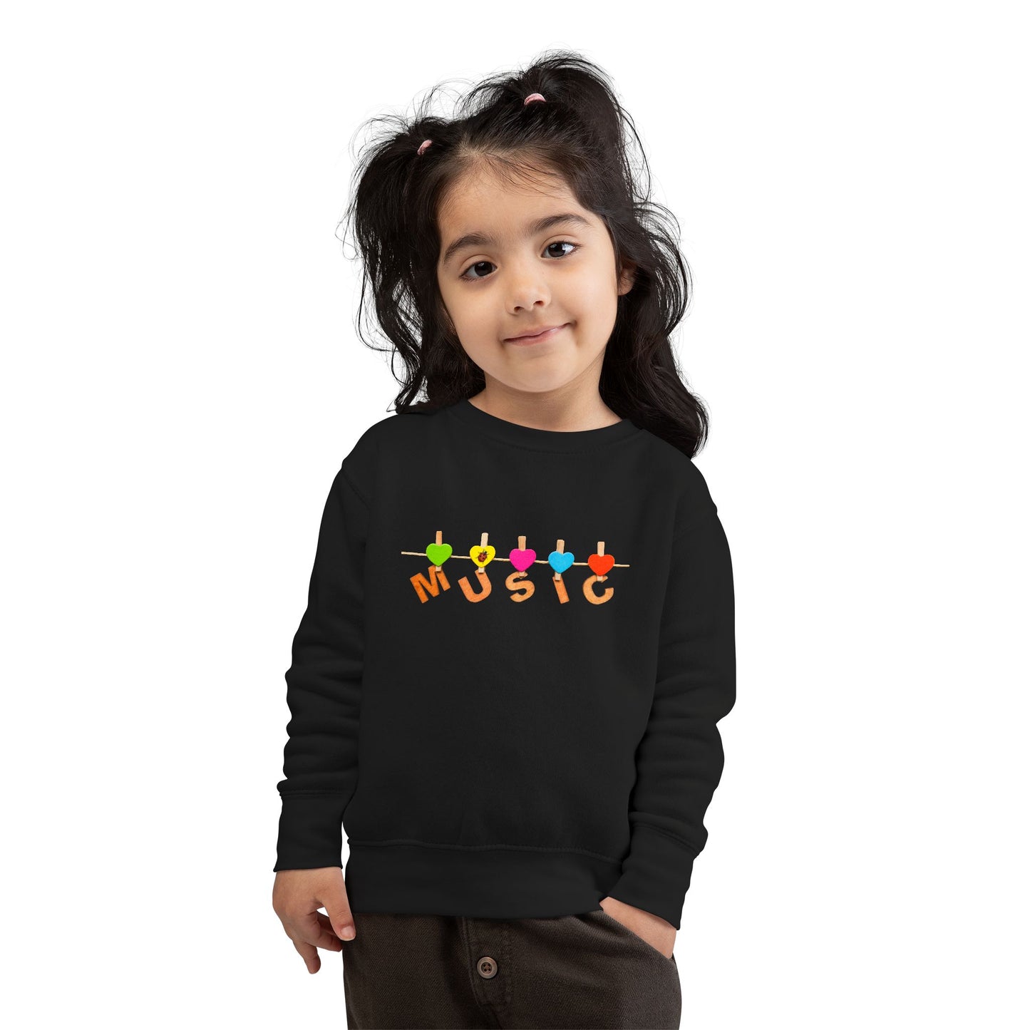 Girl wearing a black toddler sweatshirt with colorful letters hanging with clothespins to spell 'MUSIC'