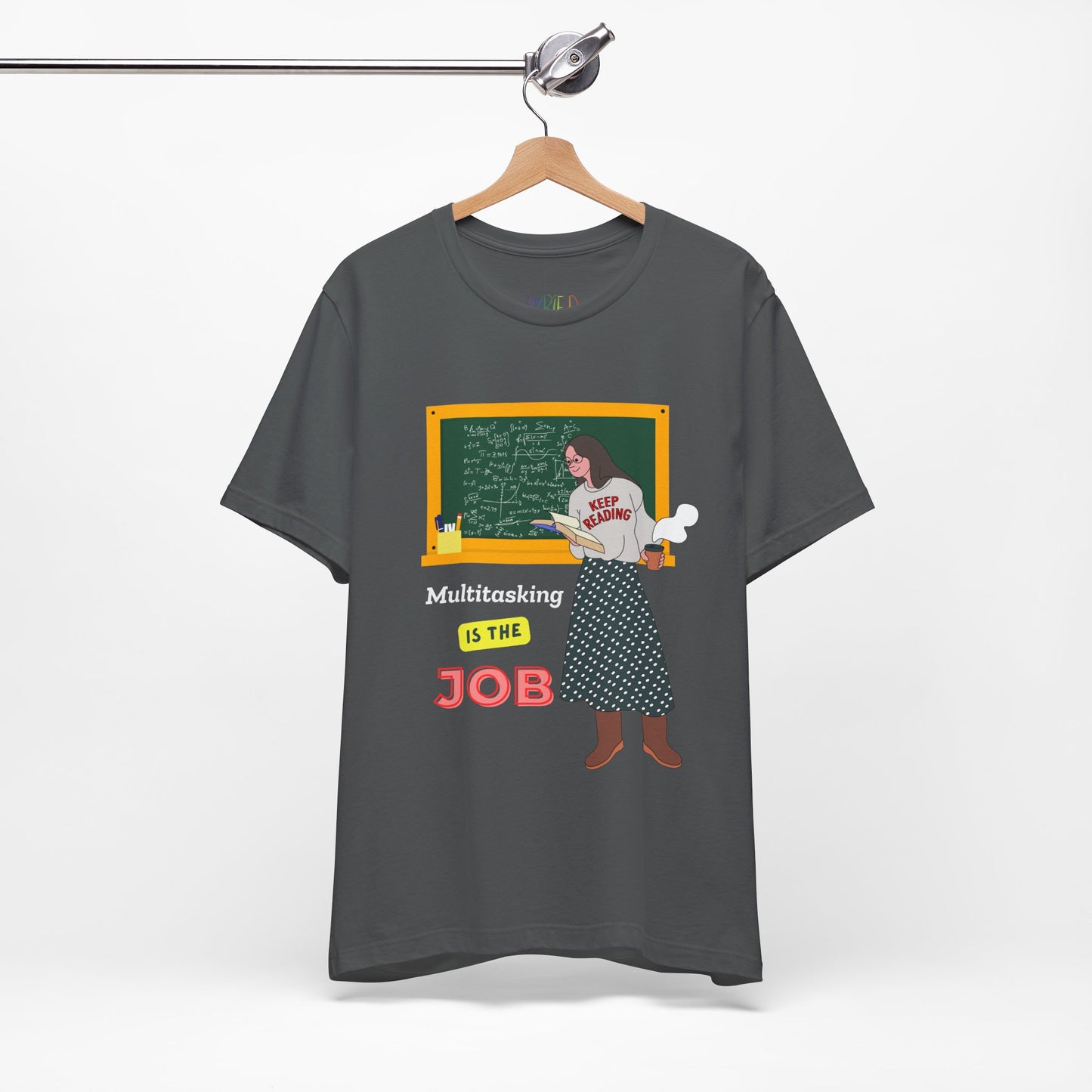 Dark gray t-shirt with a graphic design of a woman at a chalkboard, an open book in one hand and steaming coffee in the other, text 'Multitasking is the Job' 