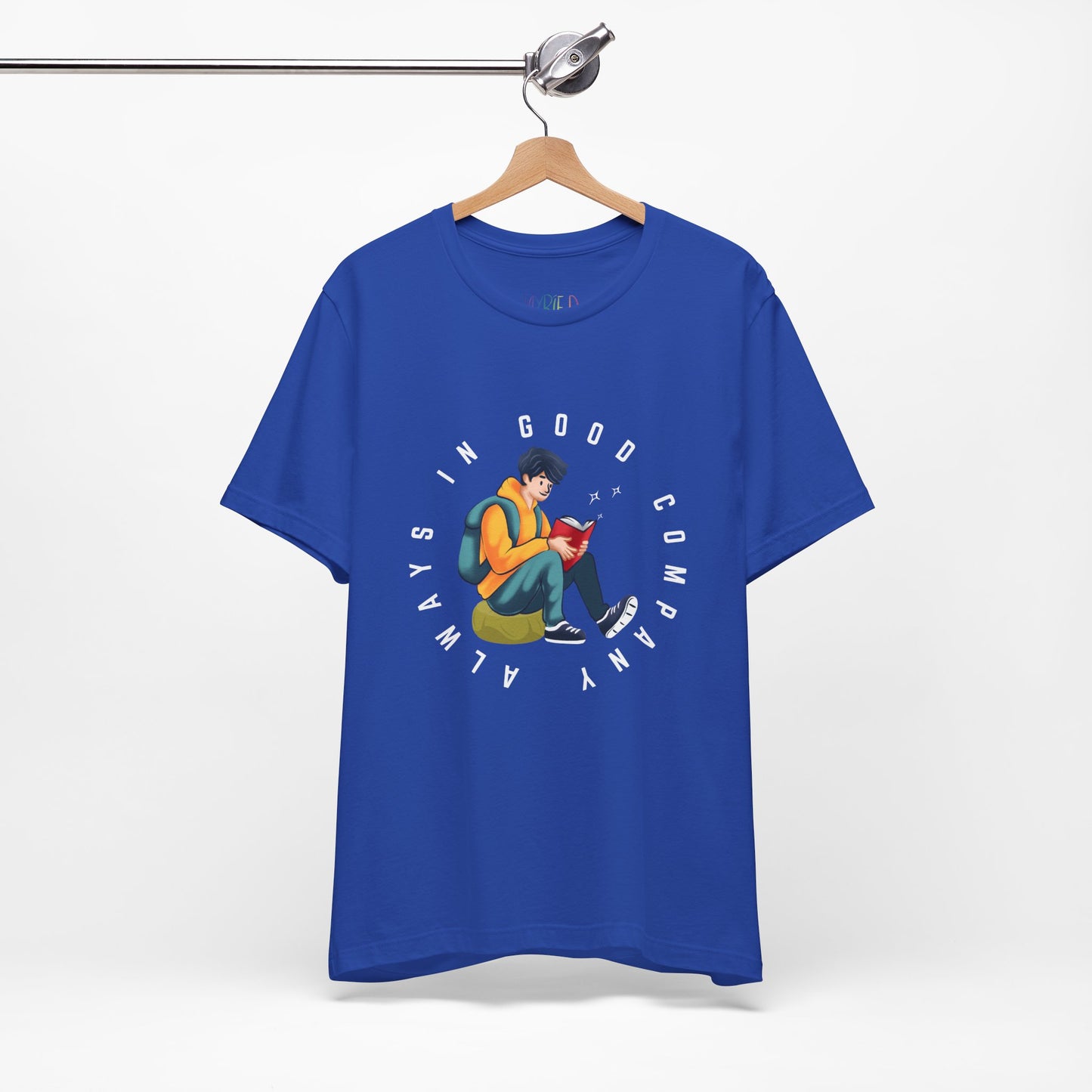 Blue t-shirt with a graphic design of a person reading a book, sitting on a green bag, with text 'Always In Good Company' 