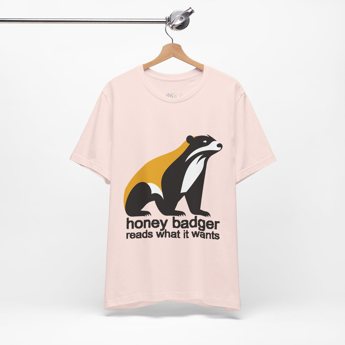 Soft pink t-shirt featuring a large black yellow and white badger with text "honey badger reads what it wants"