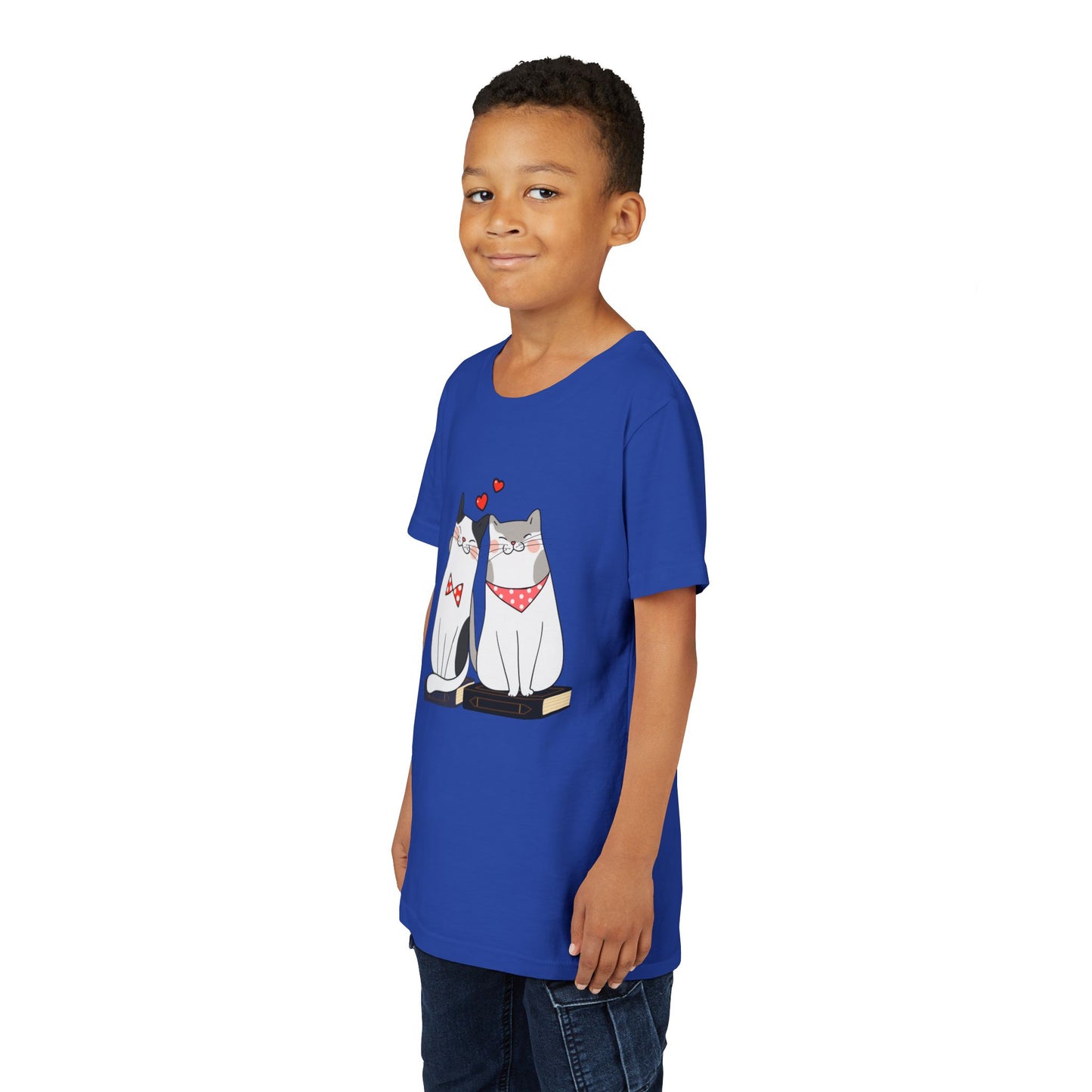 Boy wearing a blue t-shirt with two cats snuggled up on books