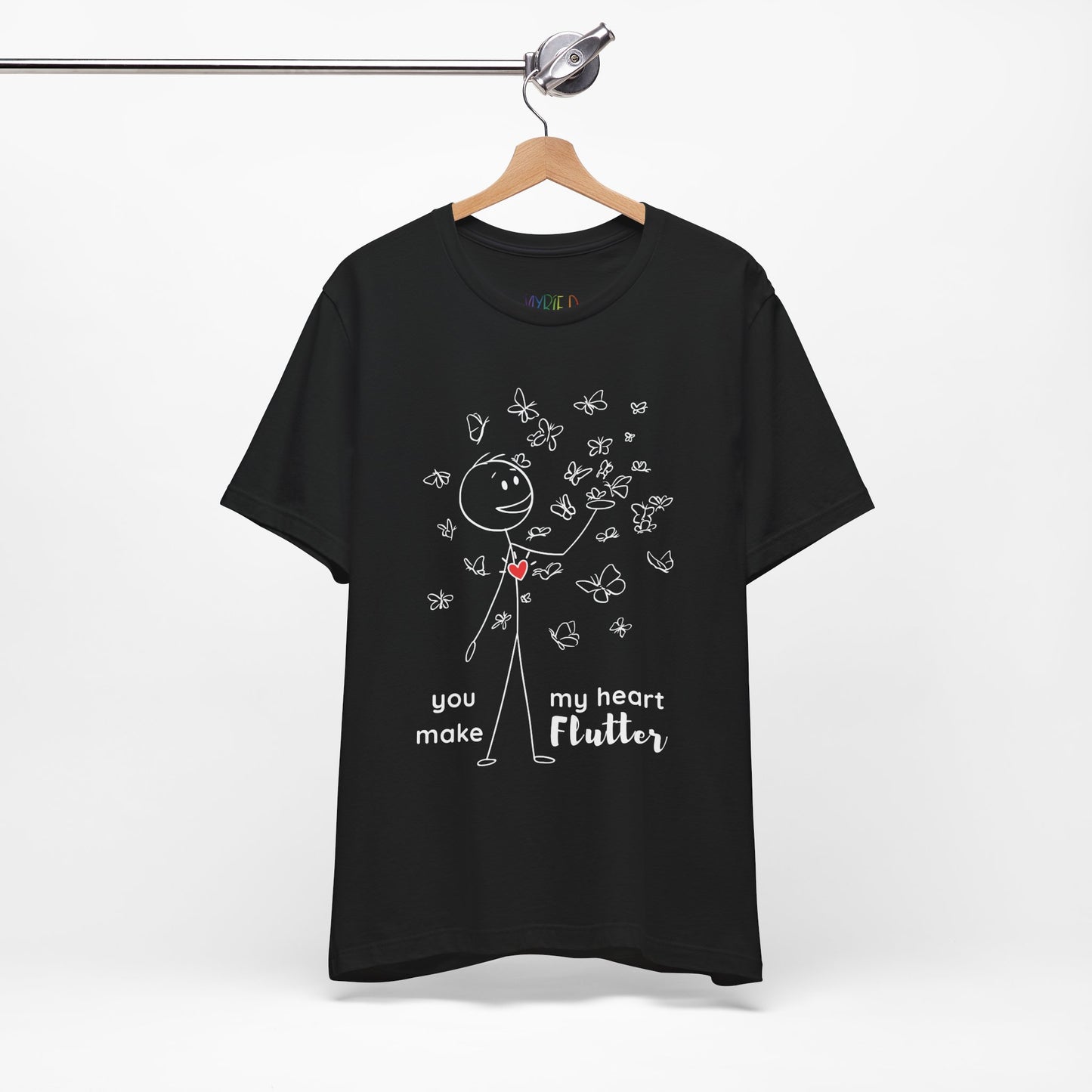 Black t-shirt with a stick figure surrounded by butterflies and a red heart beating on his chest, text 'You Make My Heart Flutter'