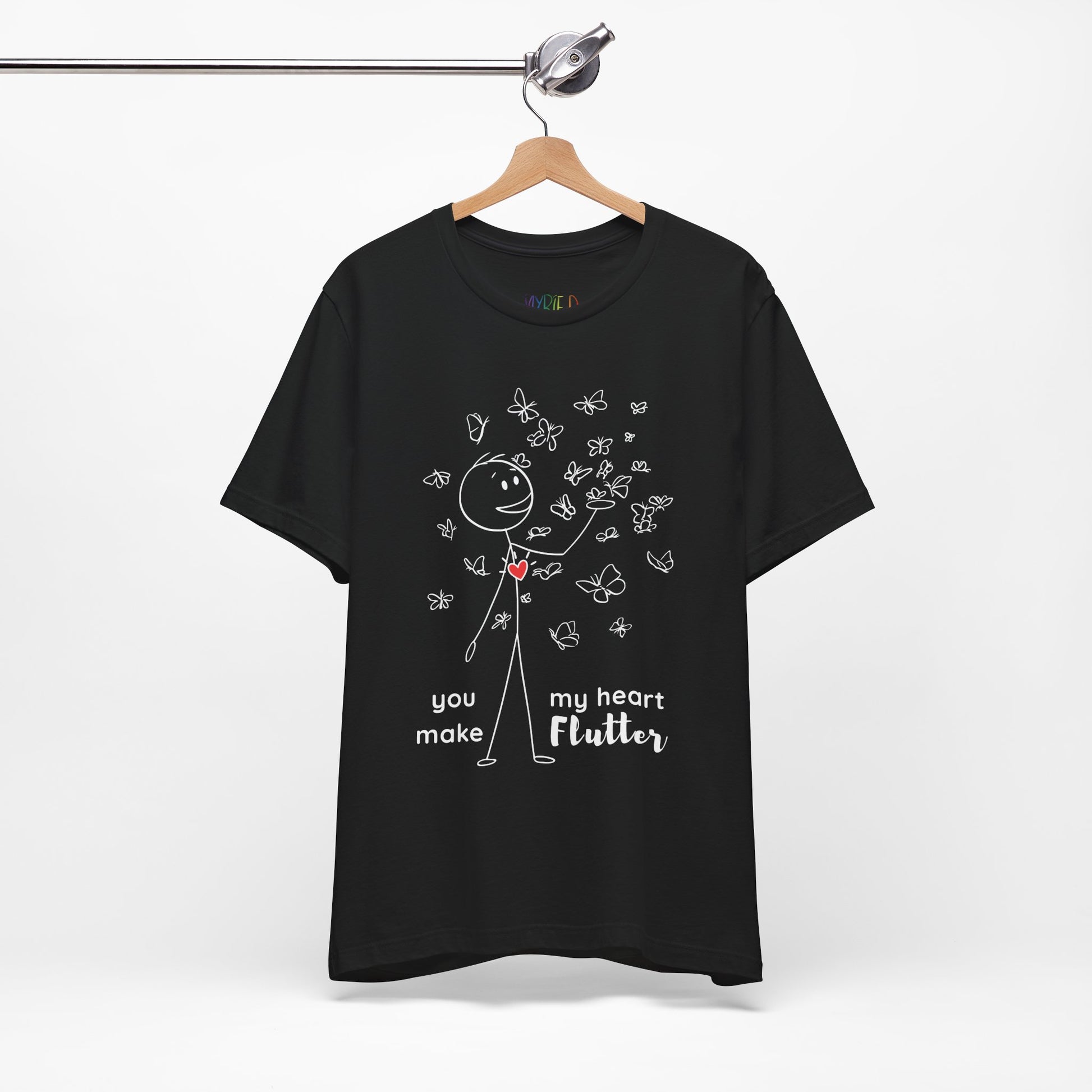Black t-shirt with a stick figure surrounded by butterflies and a red heart beating on his chest, text 'You Make My Heart Flutter'