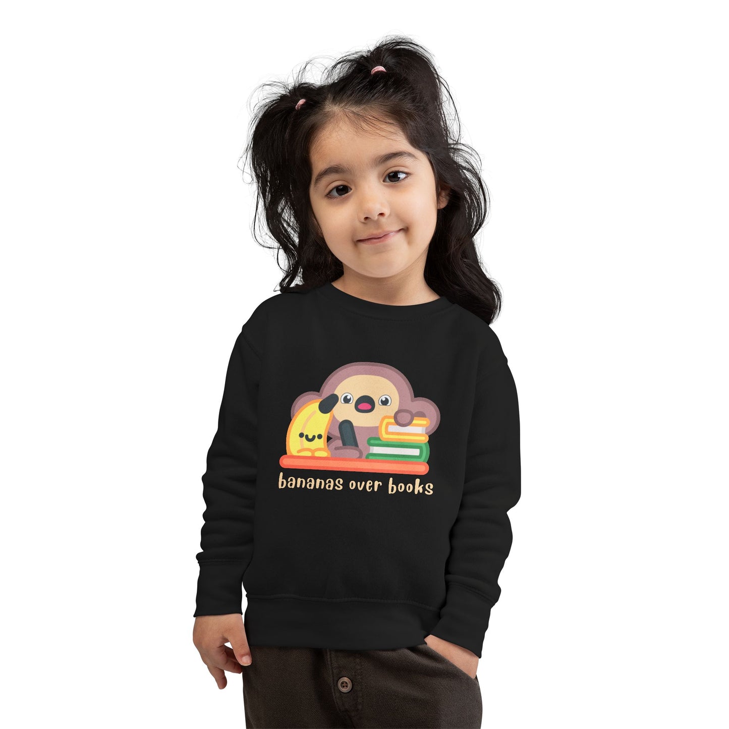 Girl wearing a black toddler sweatshirt with a cartoon monkey and banana writing desk design 