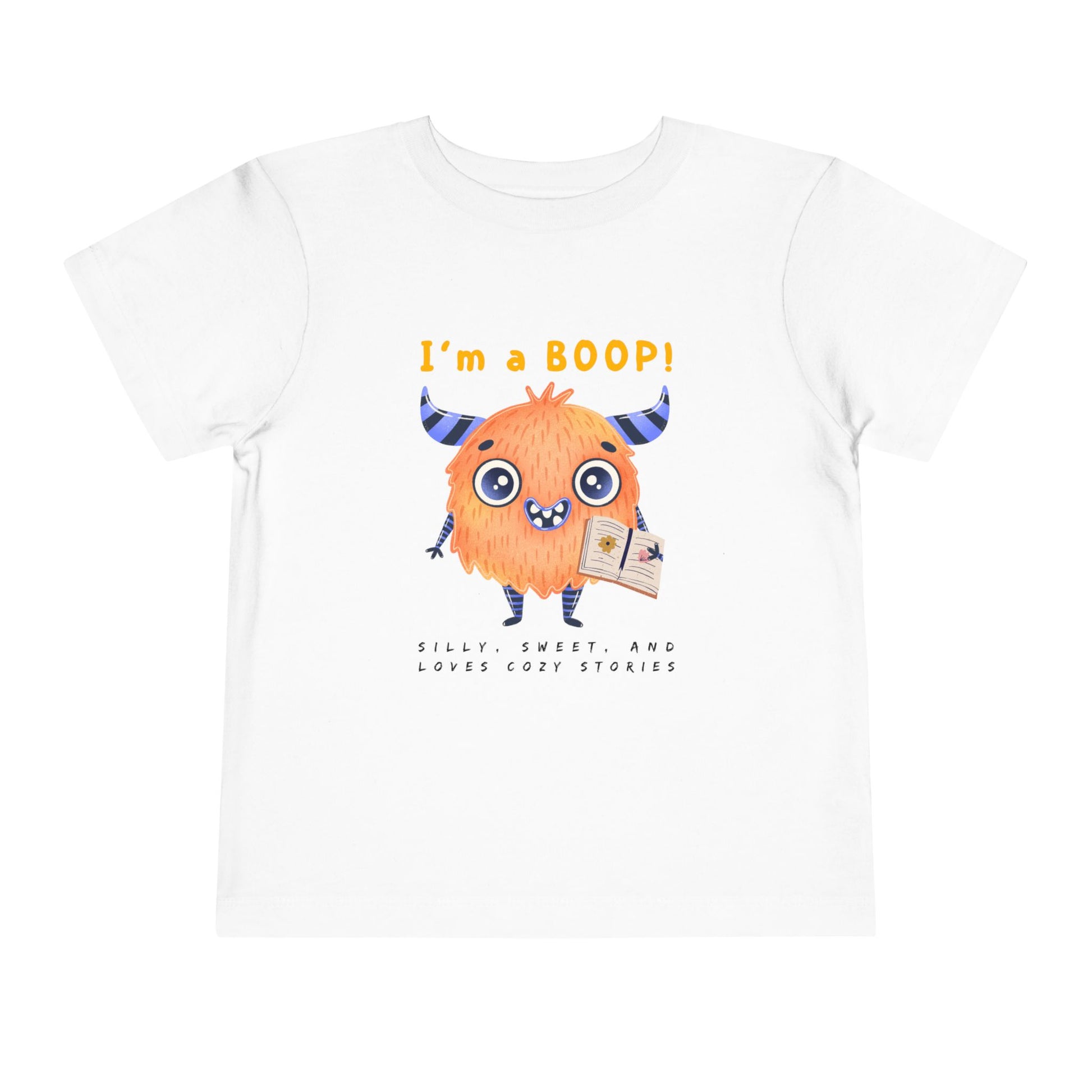 White toddler personality t-shirt with a cartoon monster holding a book, proudly proclaiming 'I'm A BOOP!' Sub-text "Silly, Sweet, And Loves Cozy Stories' on a white background