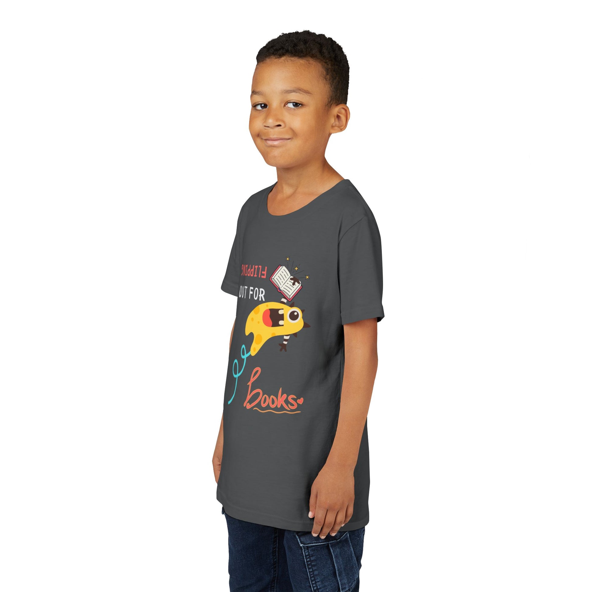 Boy wearing a gray t-shirt with a yellow monster holding a book while flipping backwards through the air and playful text 'Flipping Out For Books'