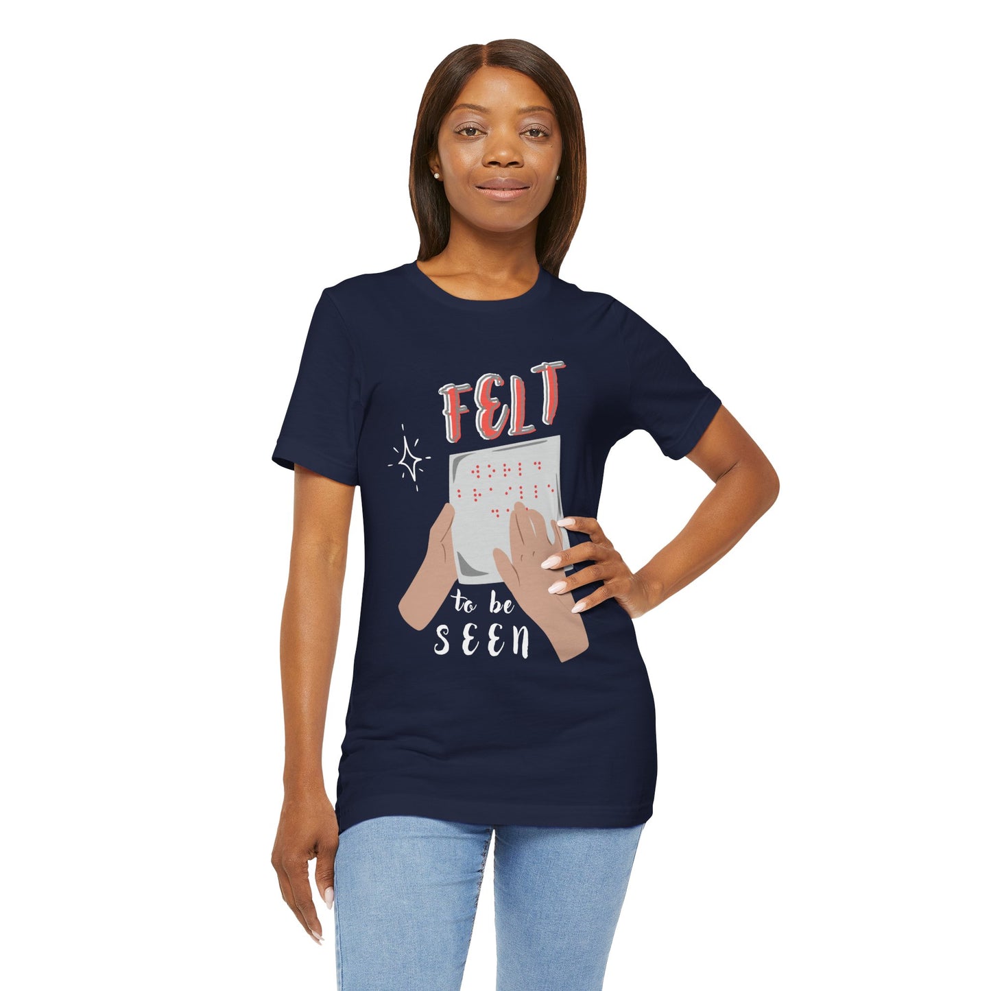 Woman wearing a navy blue t-shirt with graphic design of hands reading braille text and 'Felt To Be Seen' messaging 
