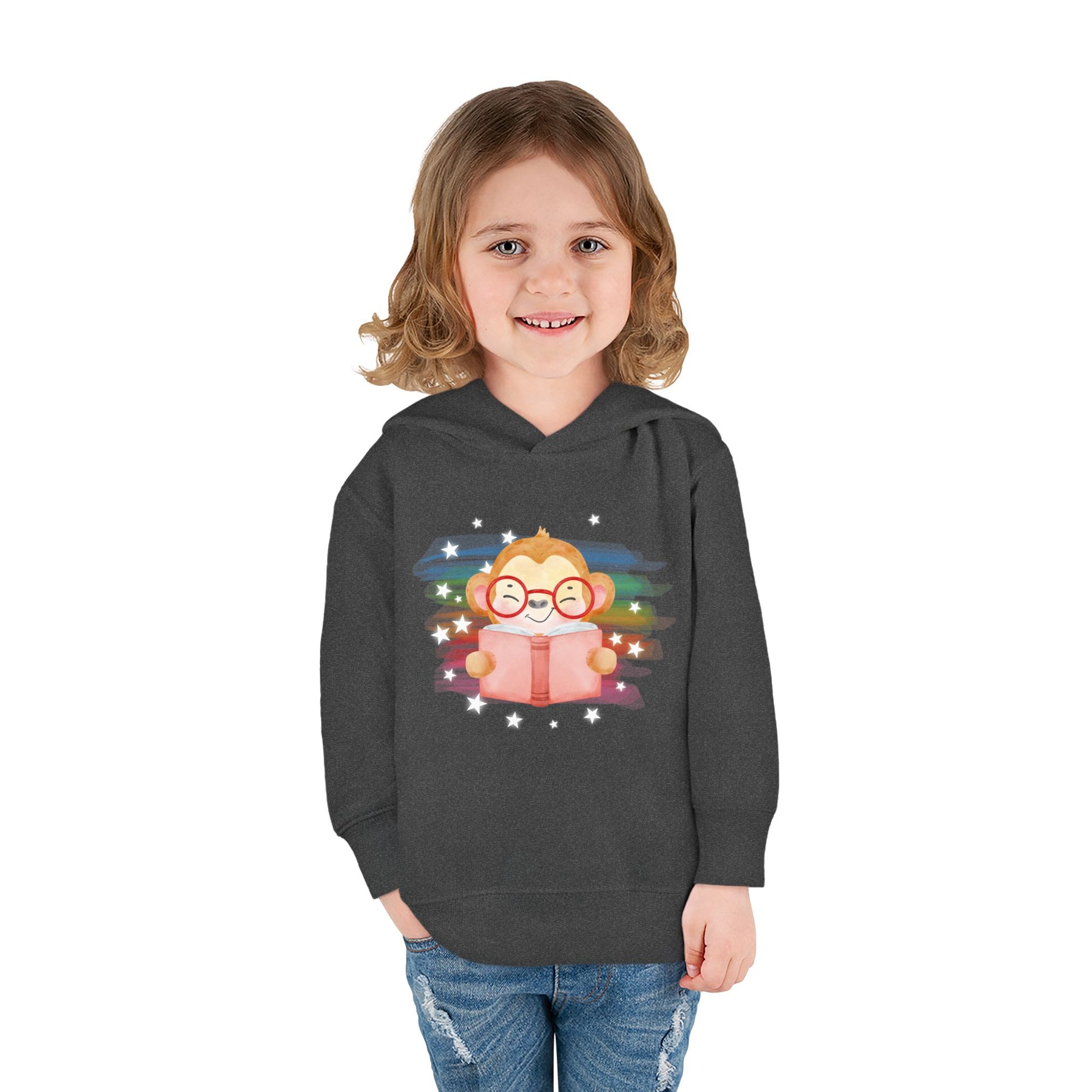 Girl wearing a dark gray toddler hoodie with a cartoon monkey wearing glasses, reading a book and surrounded by stars 