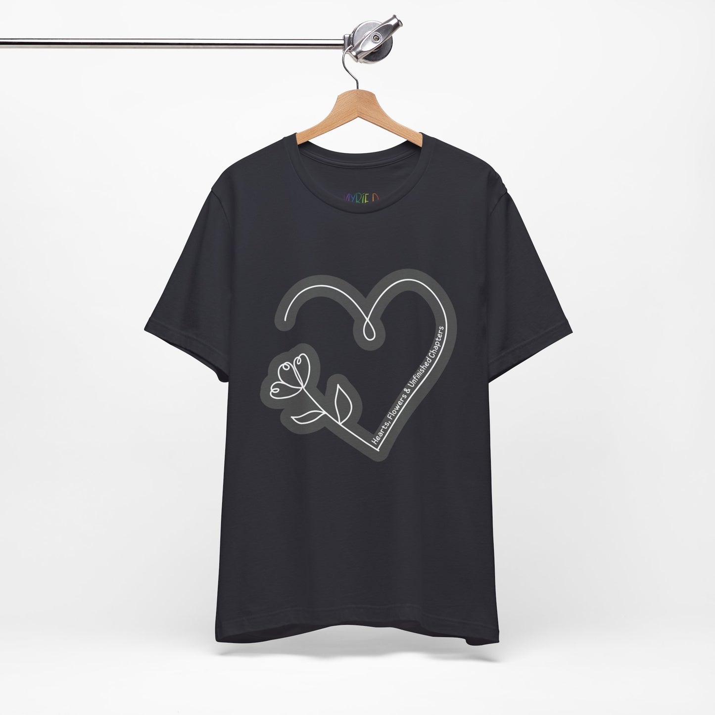 Dark grey t-shirt with a gray heart and flower sketched design and text 'Hearts, Flowers & Unfinished Chapters'