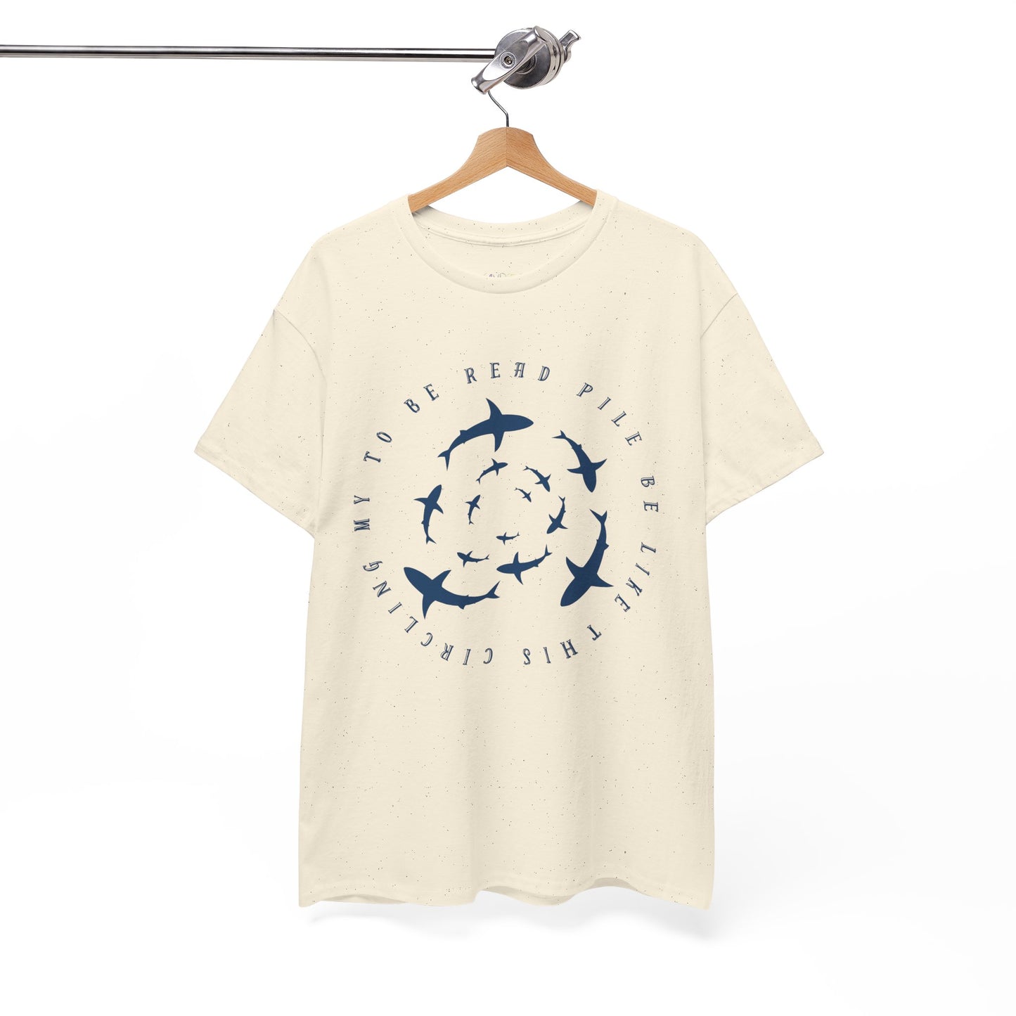 Beige t-shirt with white graphic sharks in various sizes circling and text 'circling my to be read pile be like this' 