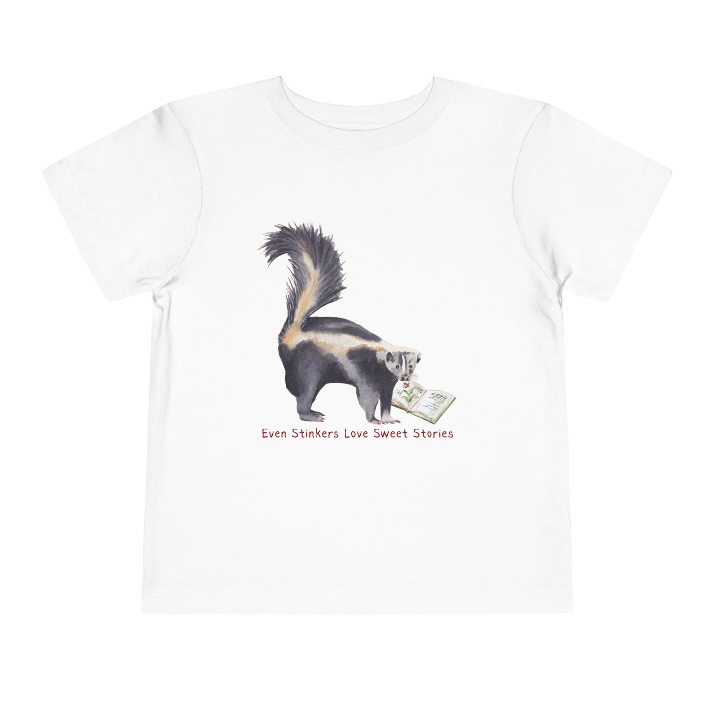 White toddler t-shirt with a skunk reading a book and text 'Even Stinkers Love Sweet Stories' 