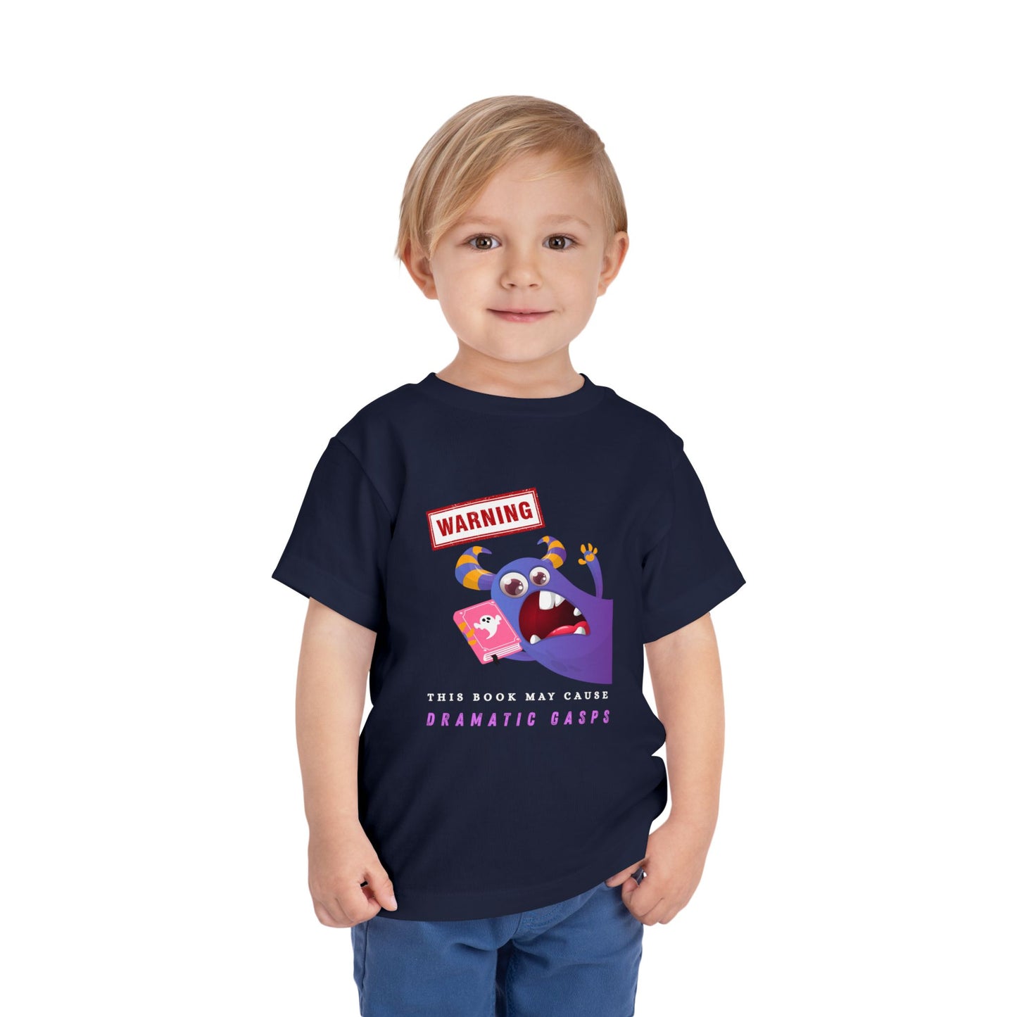 Child wearing a navy blue toddler t-shirt with an open mouth purple monster holding a pink book and a WARNING ' This Book May Cause Dramatic Gasps'